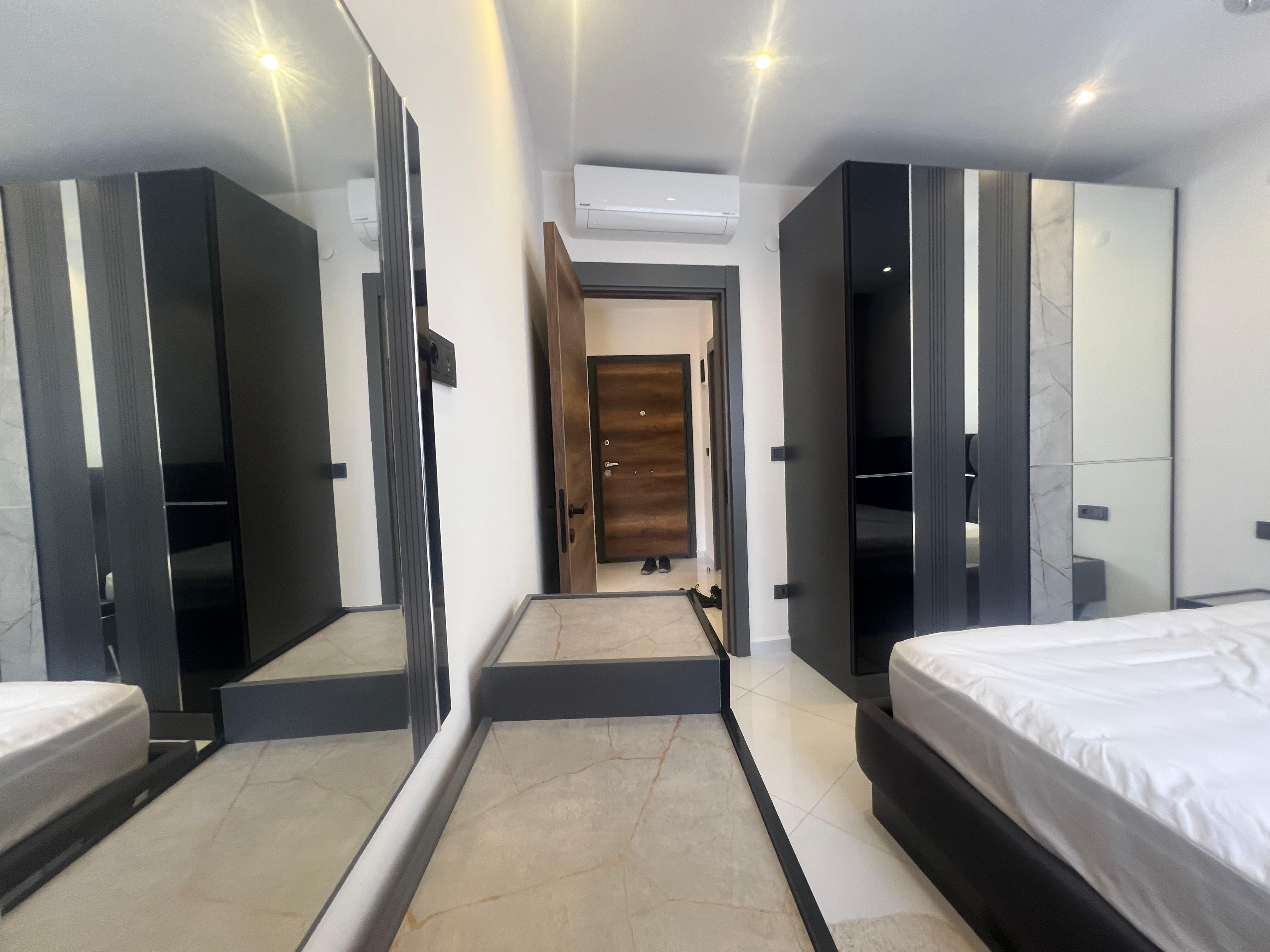 Bedroom with a mirrored wardrobe and wall-mounted television in an apartment