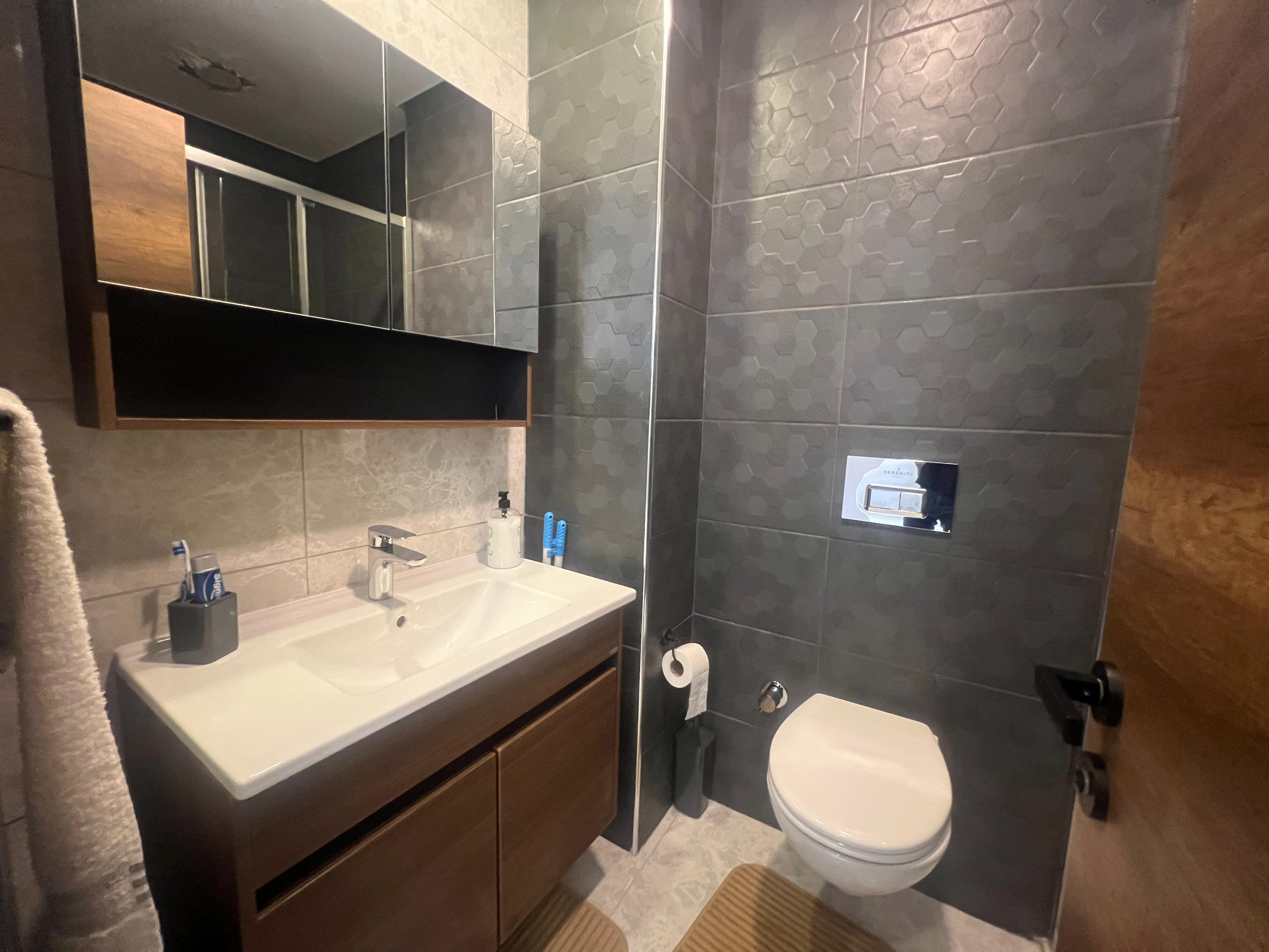 Bathroom with a white vanity and wall-mounted toilet in an apartment in Mahmutlar