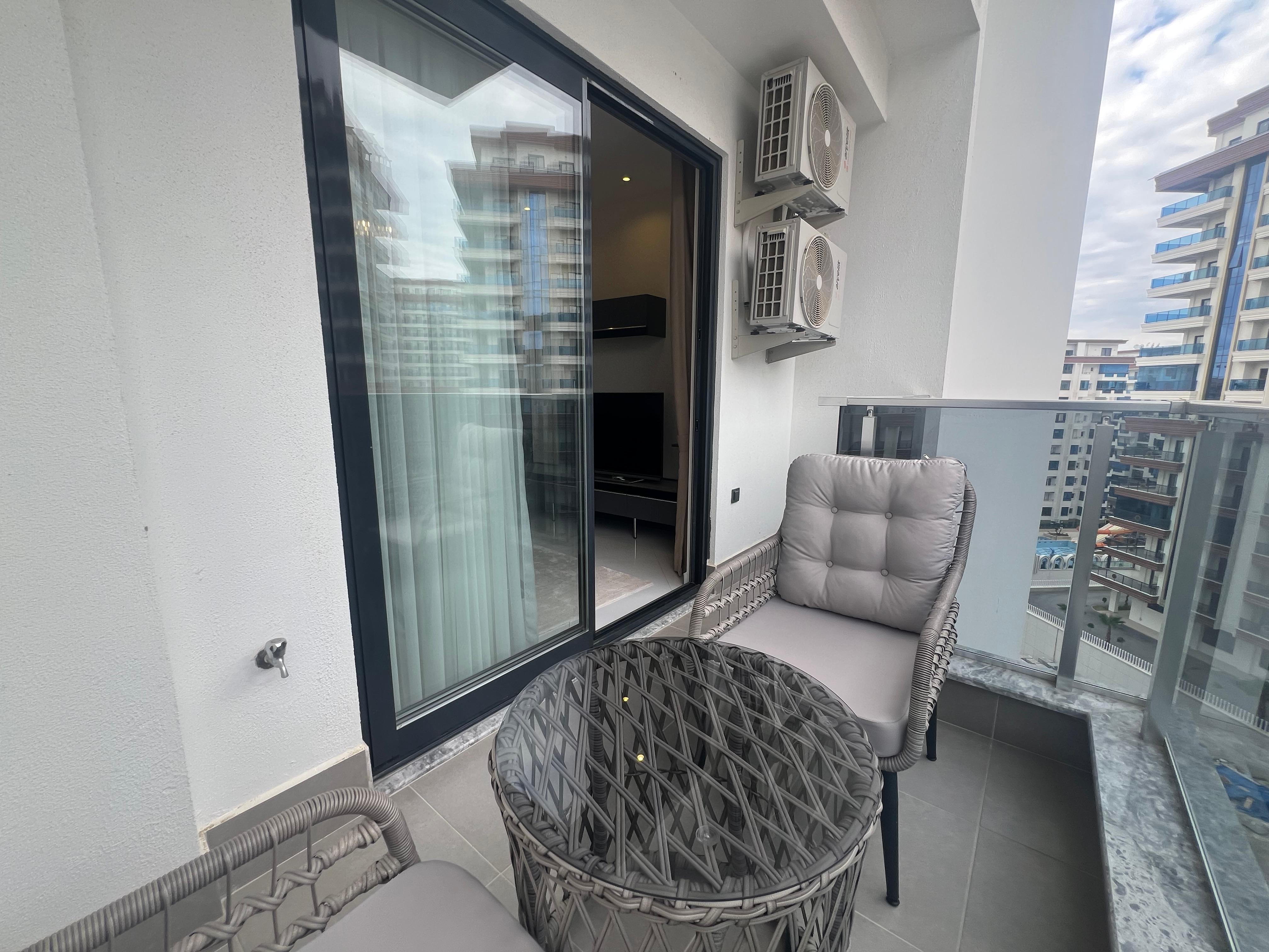 Glazed balcony with a woven table and two chairs at a home in Turkey