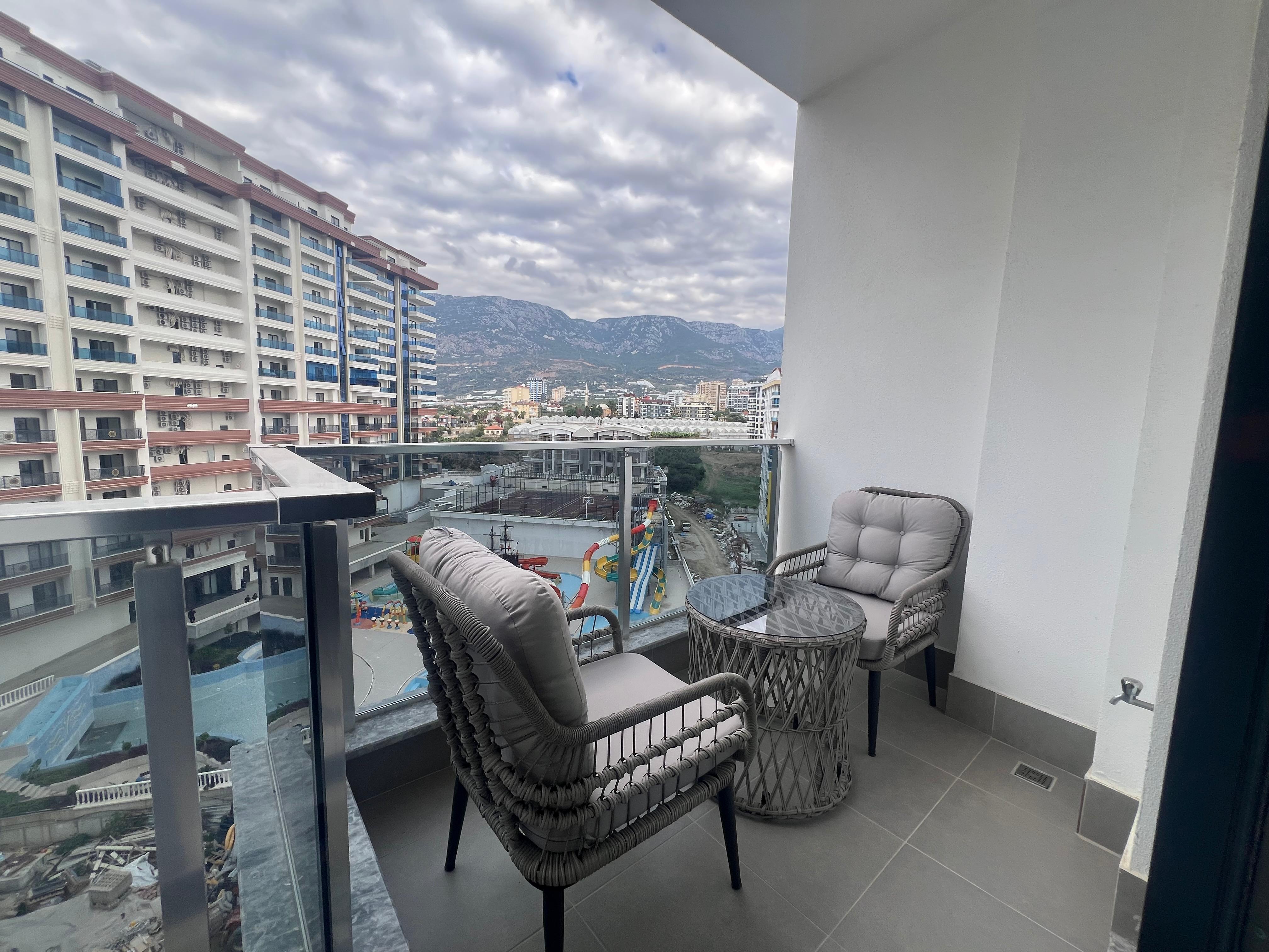 Balcony with glass railing and chairs overlooking the pool at a residence in Mahmutlar