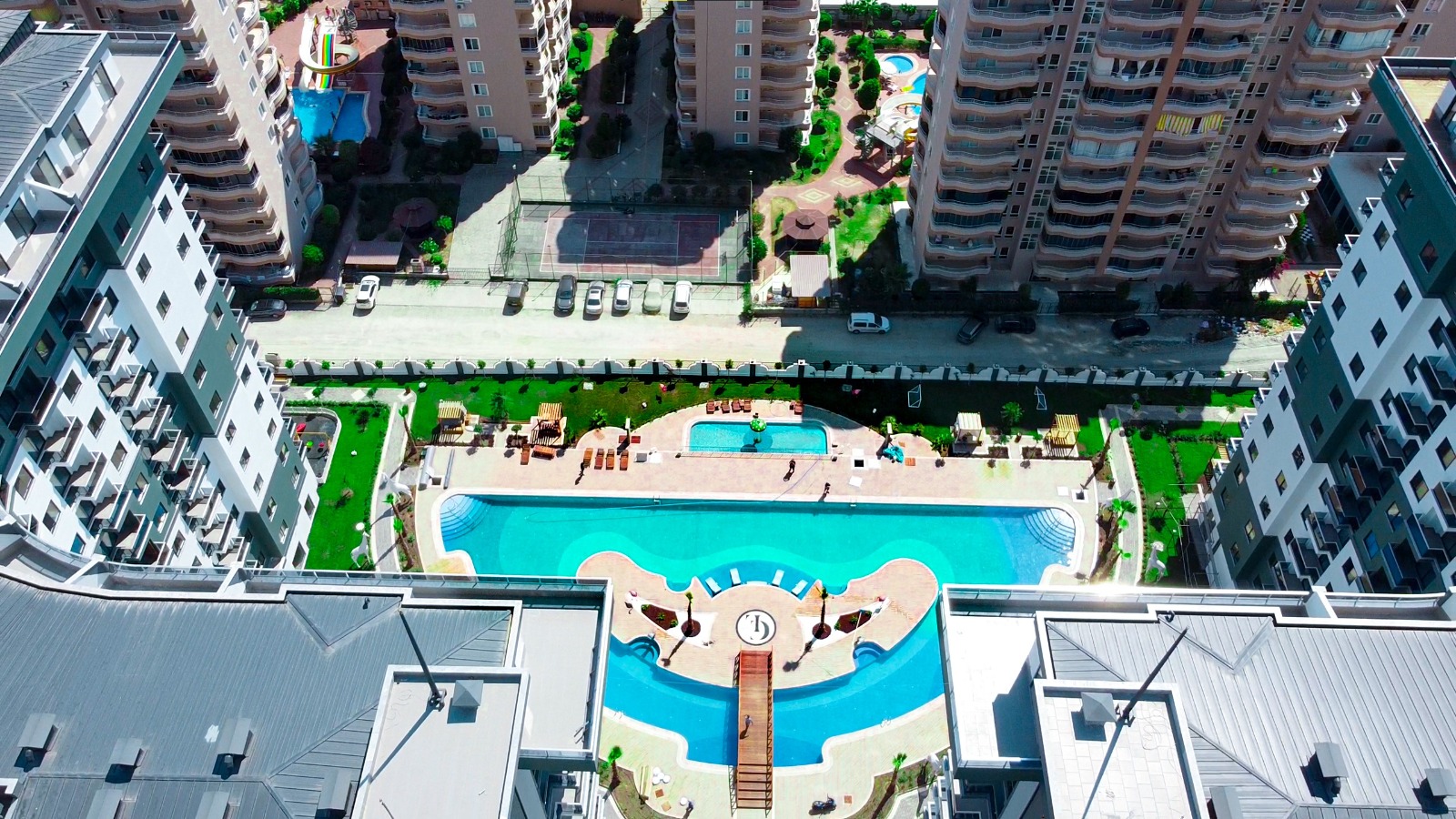 Central outdoor pool with a decorative island and bridge in a complex with flats for sale in Turkey