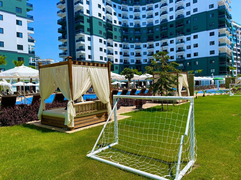 Green lawn with a curtained gazebo football goals and pool in Mahmutlar