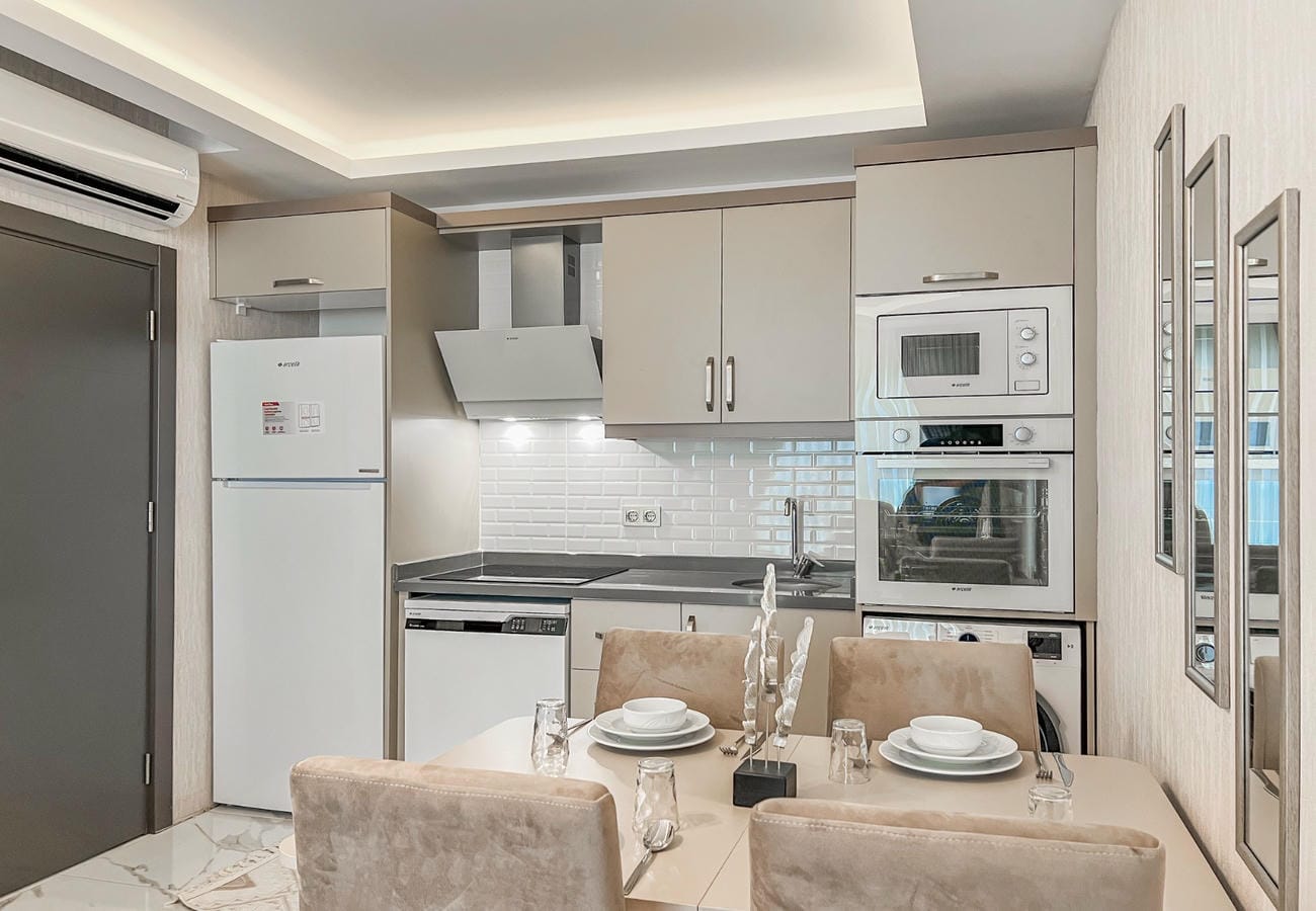 A kitchen with white refrigerator, built-in appliances and a set dining table in an apartment