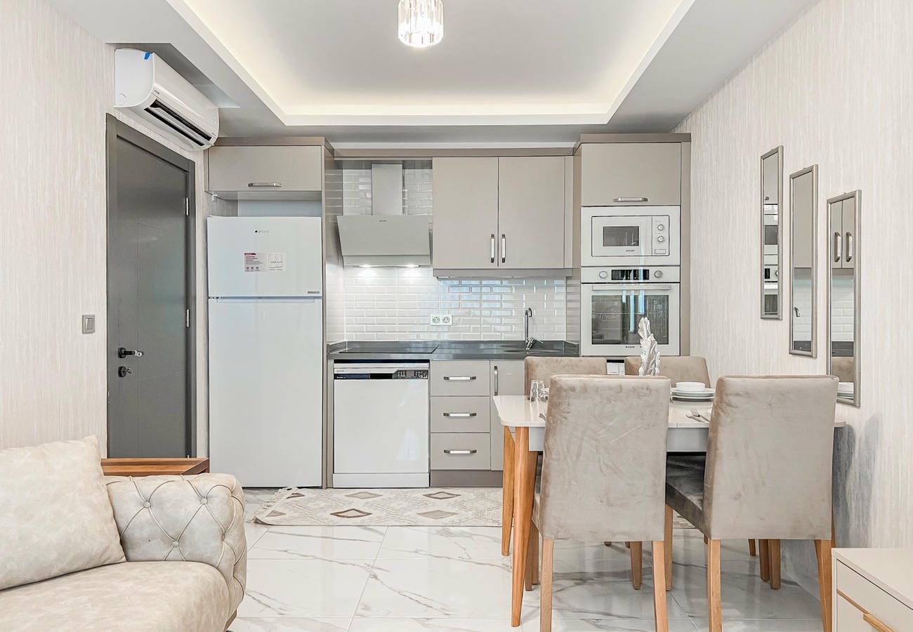 Kitchen-living room with linear cabinetry, sofa and dining area in a residence in Mahmutlar