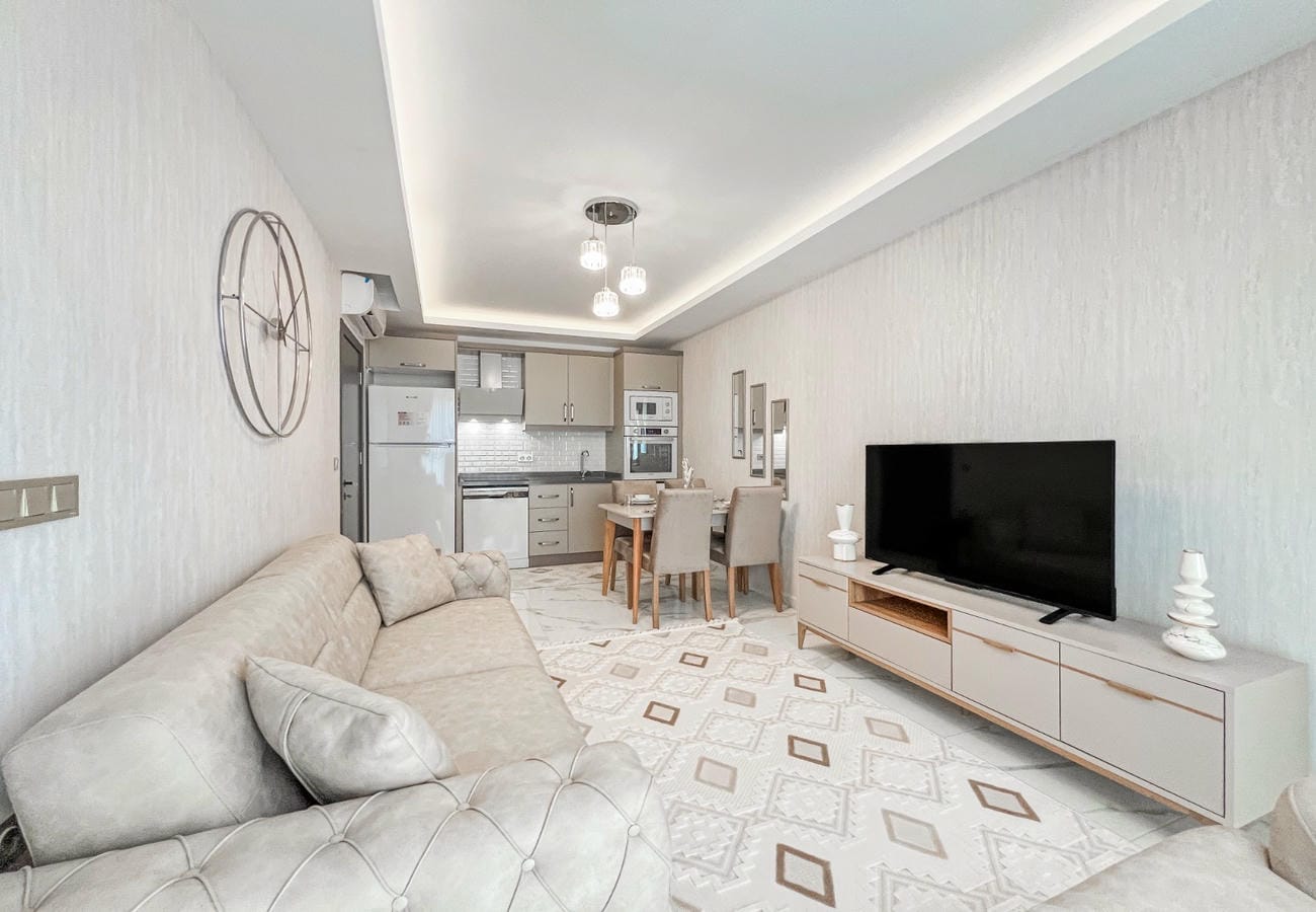 Kitchen-living room with corner sofa, dining area and television in a residence in Mahmutlar, Turkey