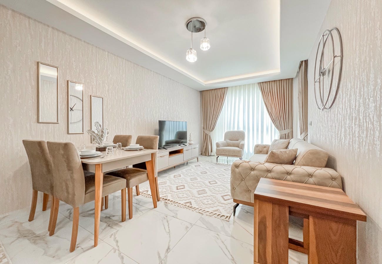 Light sofa and armchairs by the window in a kitchen-living room of an apartment