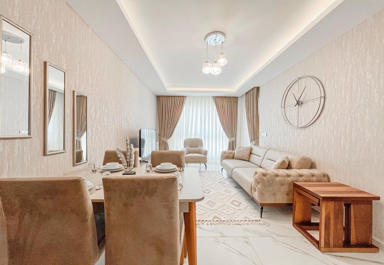 Kitchen-living room in Mahmutlar with sofa, armchairs by the window and dining area where apartments are for sale