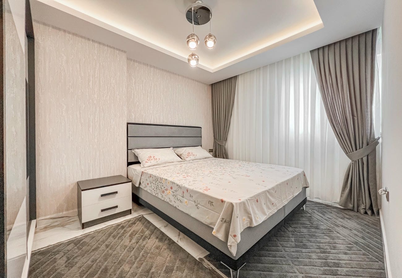 Bedroom with double bed, mirrored wardrobe and panoramic window in an apartment