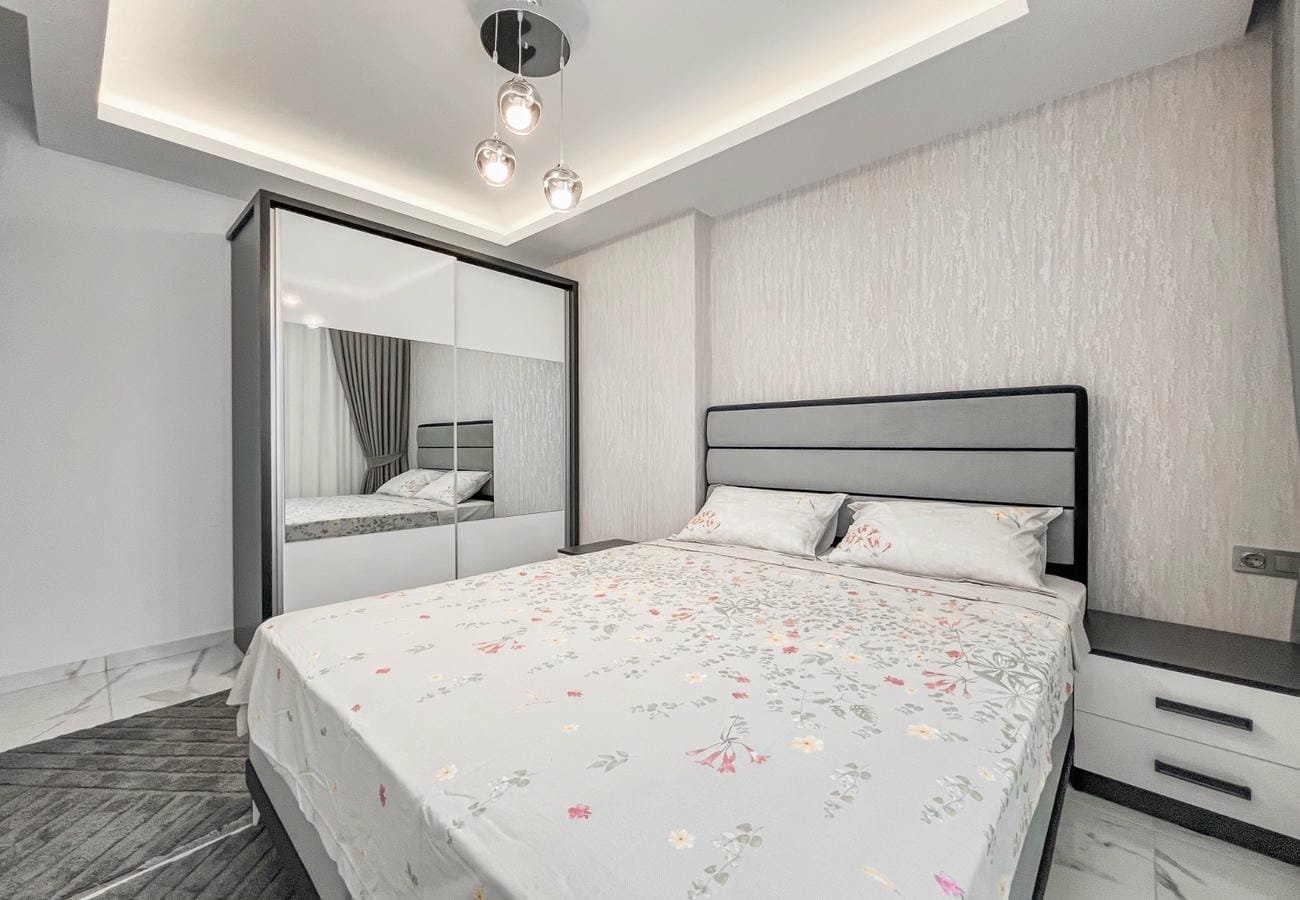 Floral bedspread and mirrored wardrobe in a bedroom of a flat in Mahmutlar