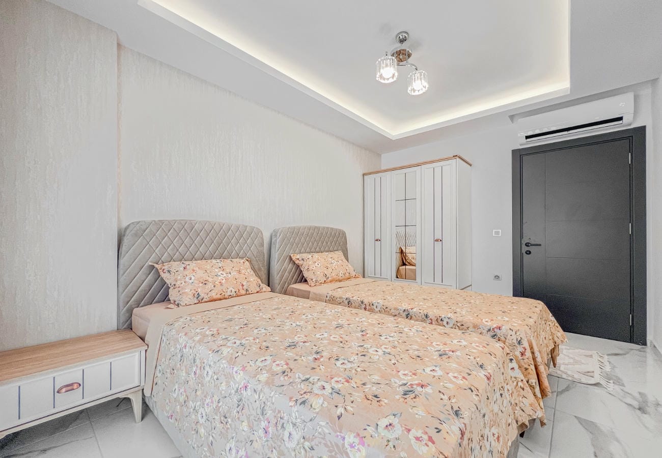 Two beds, a white wardrobe and marble floor in a home in Mahmutlar