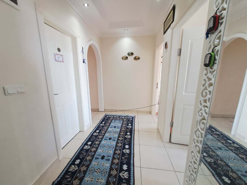 Giriş holünde mavi desenli uzun yolluk, oymalı çerçeveli ayna ve kemerli geçiş bulunan 4+1 penthouse