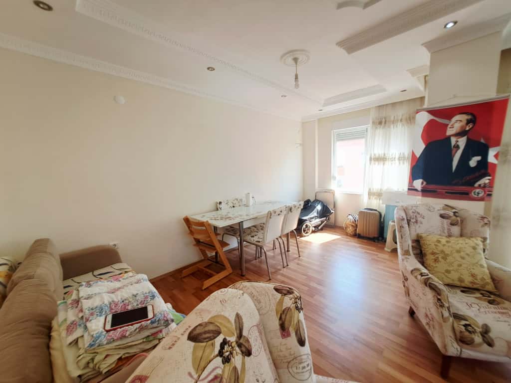 Çikcilli'de satılık 4+1 dubleksin yemek odasında örtülü masa, dört sandalye ve çiçekli koltuklar