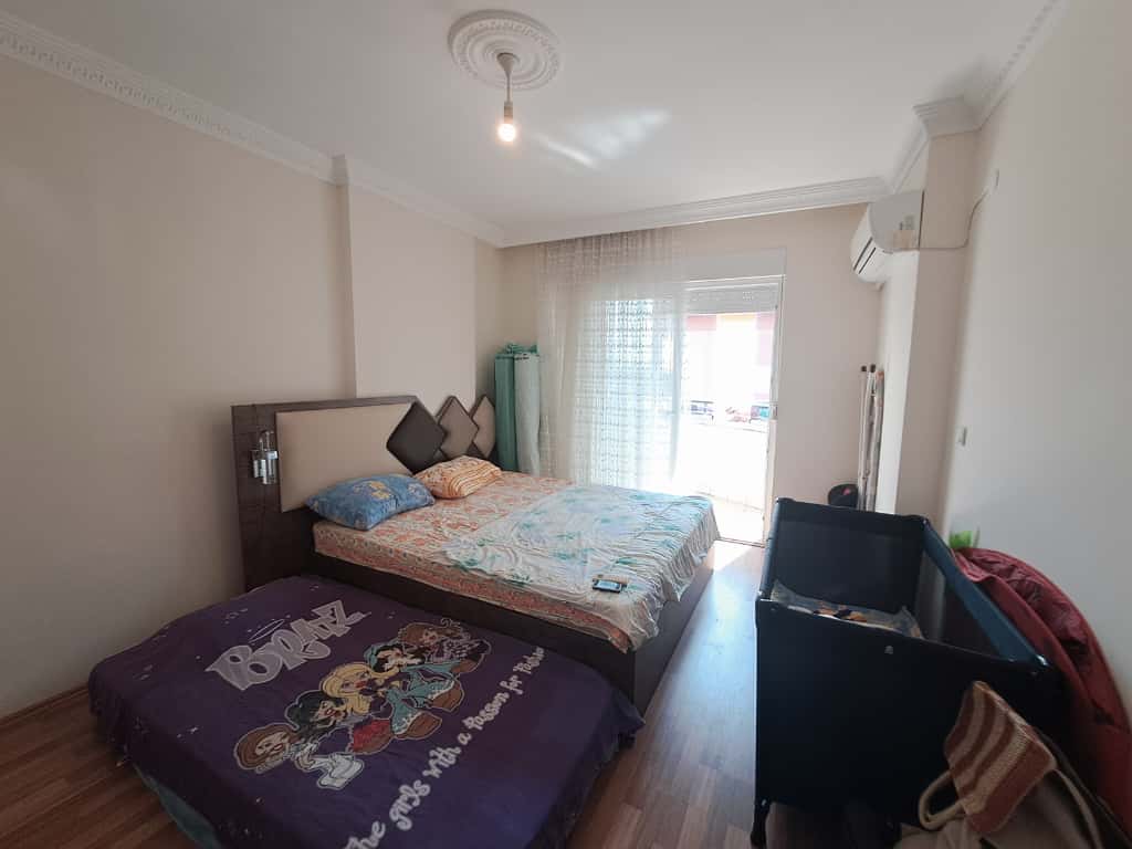 Alanya'daki dubleksin yatak odasında çift kişilik yatak, çocuk karyolası ve balkon çıkışı
