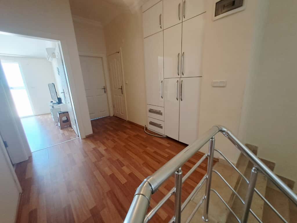Çikcilli'deki 4+1 çatı katı dairenin holünde bej basamaklı merdiven, gömme dolap ve metal korkuluk