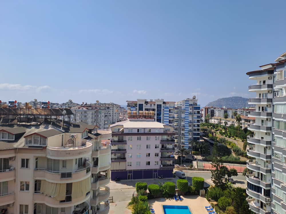 Rezidans dairelerinin bulunduğu siteden mavi havuza, yeşil çalılara ve konut bloklarına yüksekten bakış