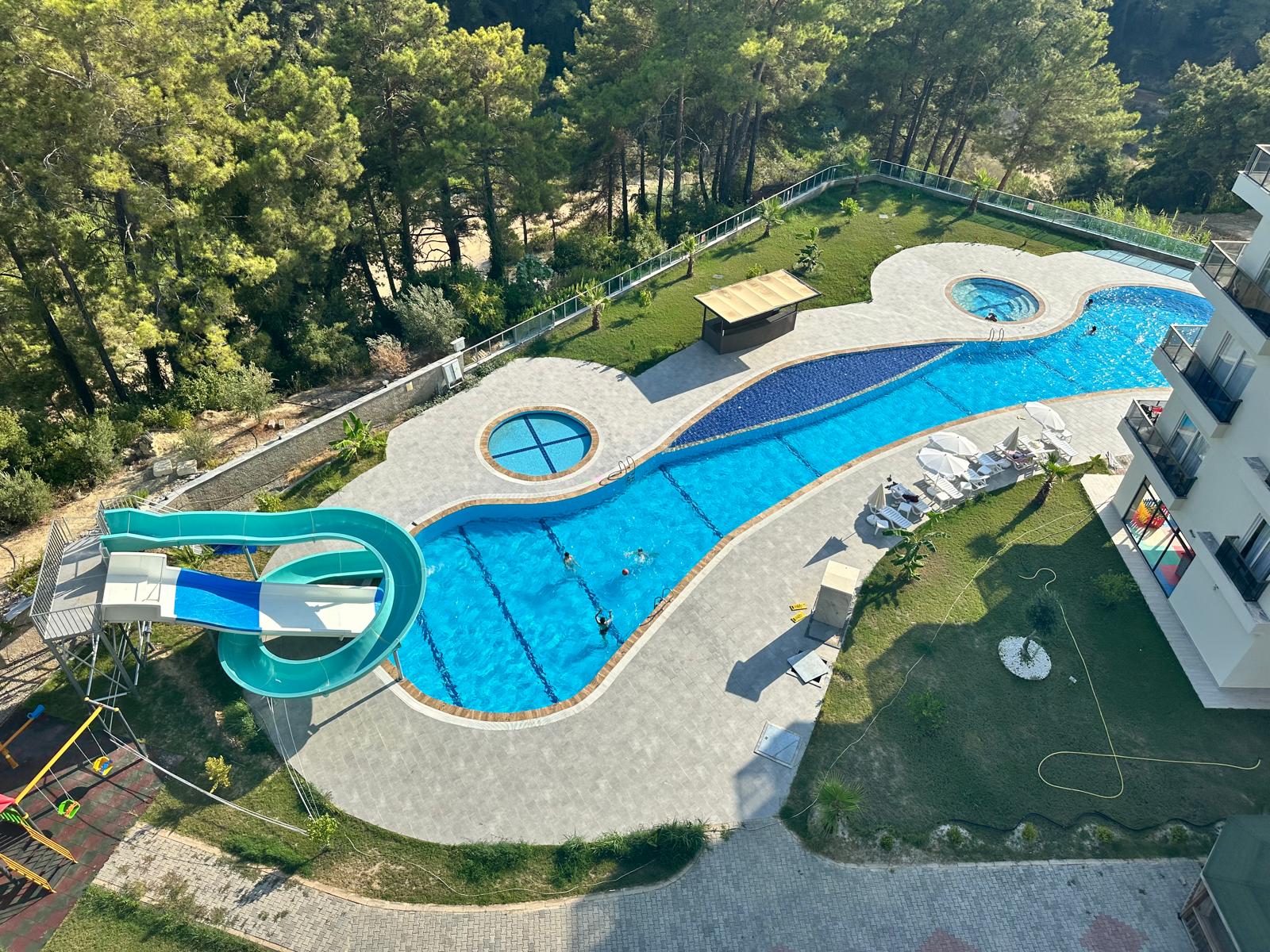 Aerial view of pools with slides and hot tubs in a complex with apartments for sale in Turkey