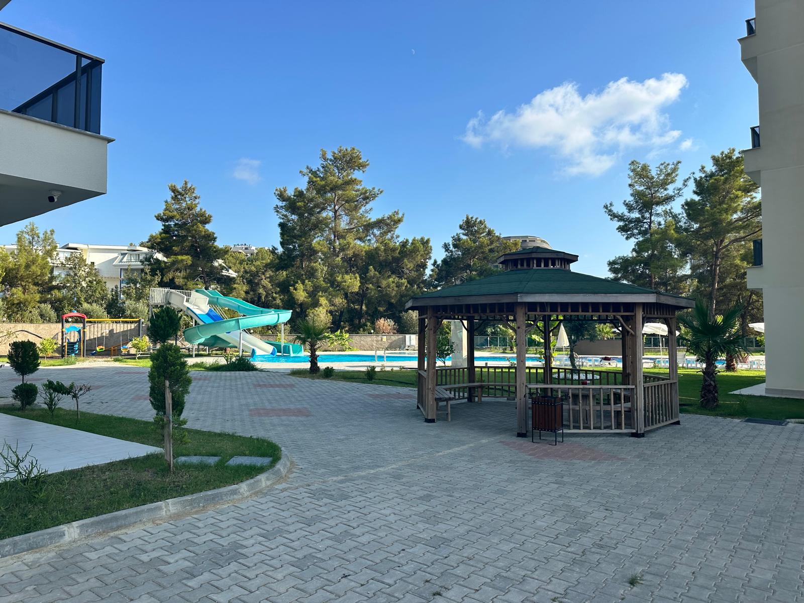 Paved grounds with a gazebo and pool in a complex with apartments for sale in Turkey