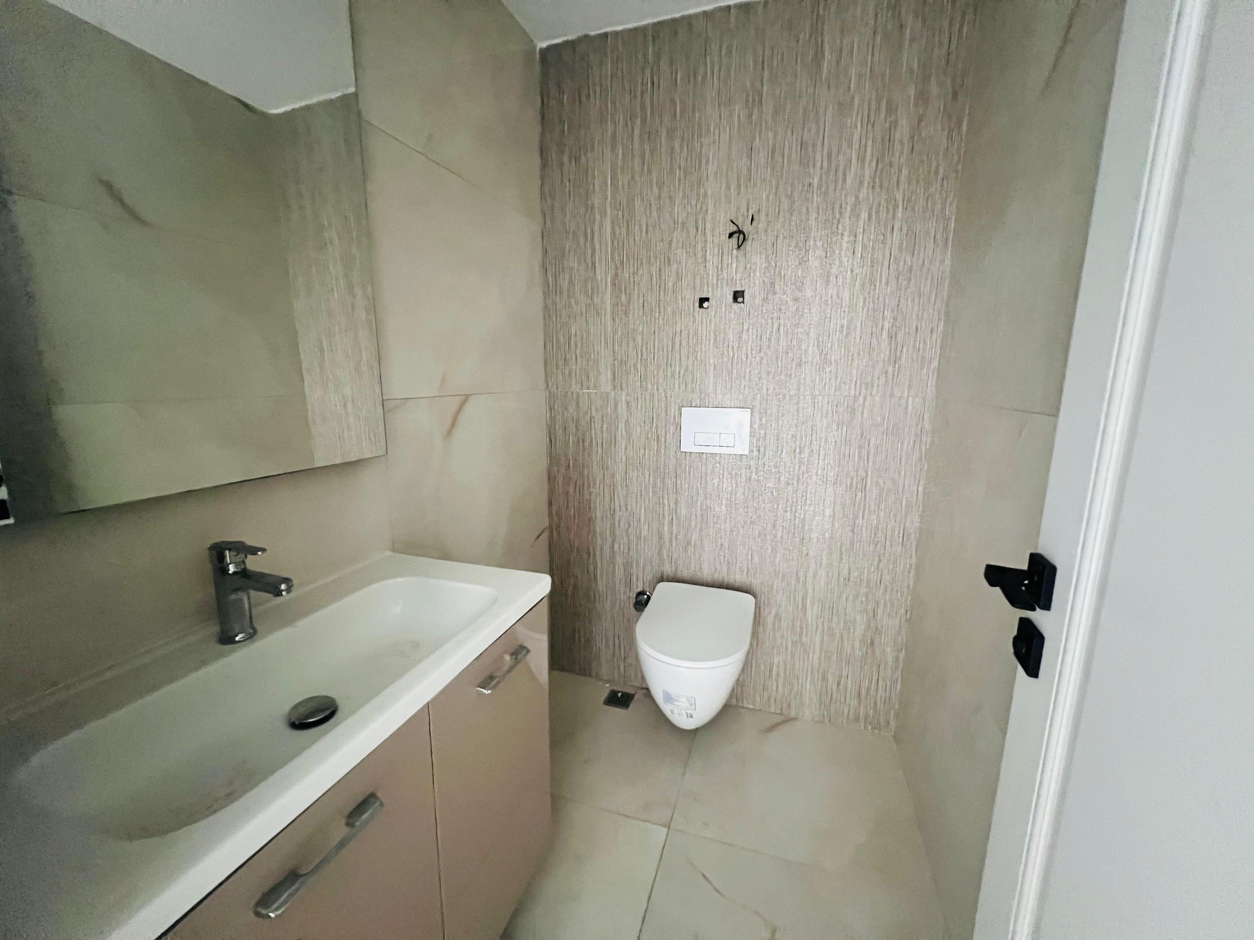 Bej fayanslı banyo Konaklı’daki dairede lavabo ve asma klozetle