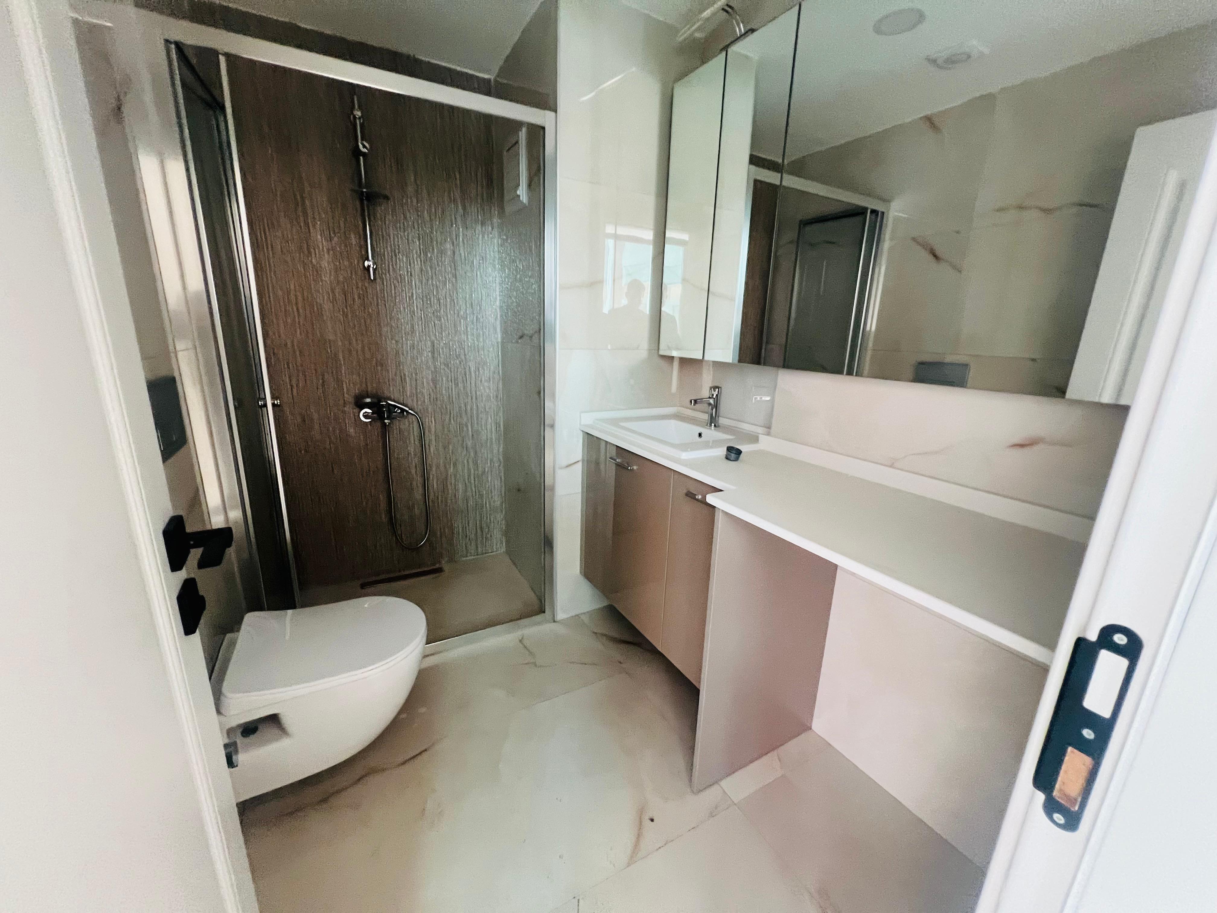 Cam duş bölmeli banyo mermersi duvar ve zemine sahip evde
