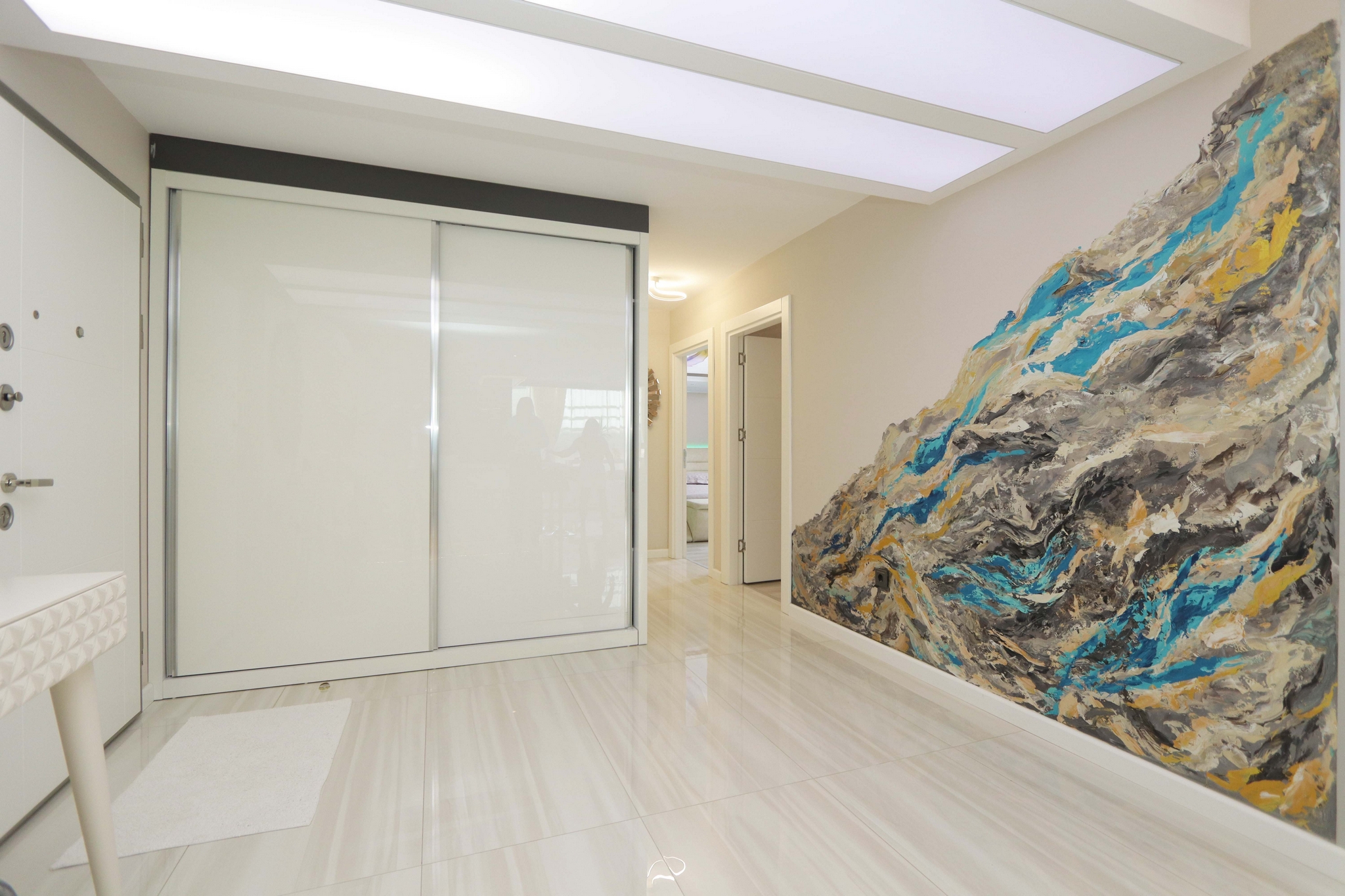 Entry hall with a built-in wardrobe, abstract artwork and round mirror in a complex with apartments