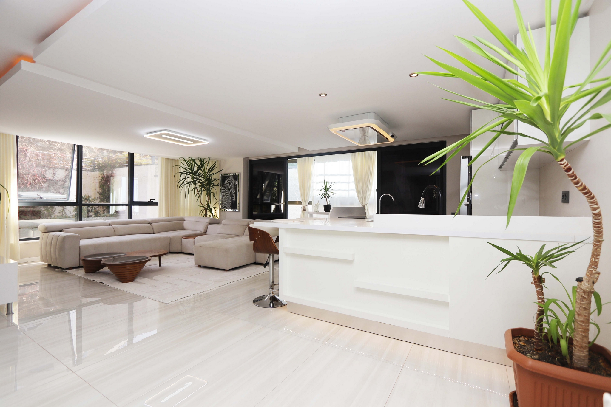 Panoramic windows and a white breakfast bar frame the kitchen-living room in a Kargicak residence