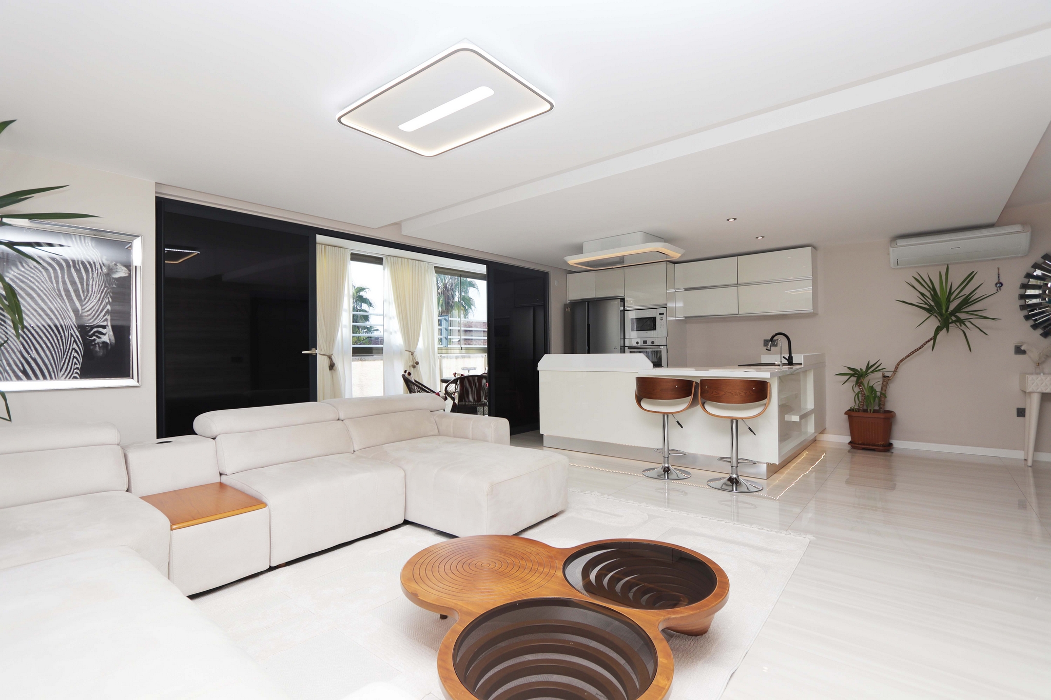 Kitchen-living room with an island, white sofa and panoramic glazing in a flat in Turkey