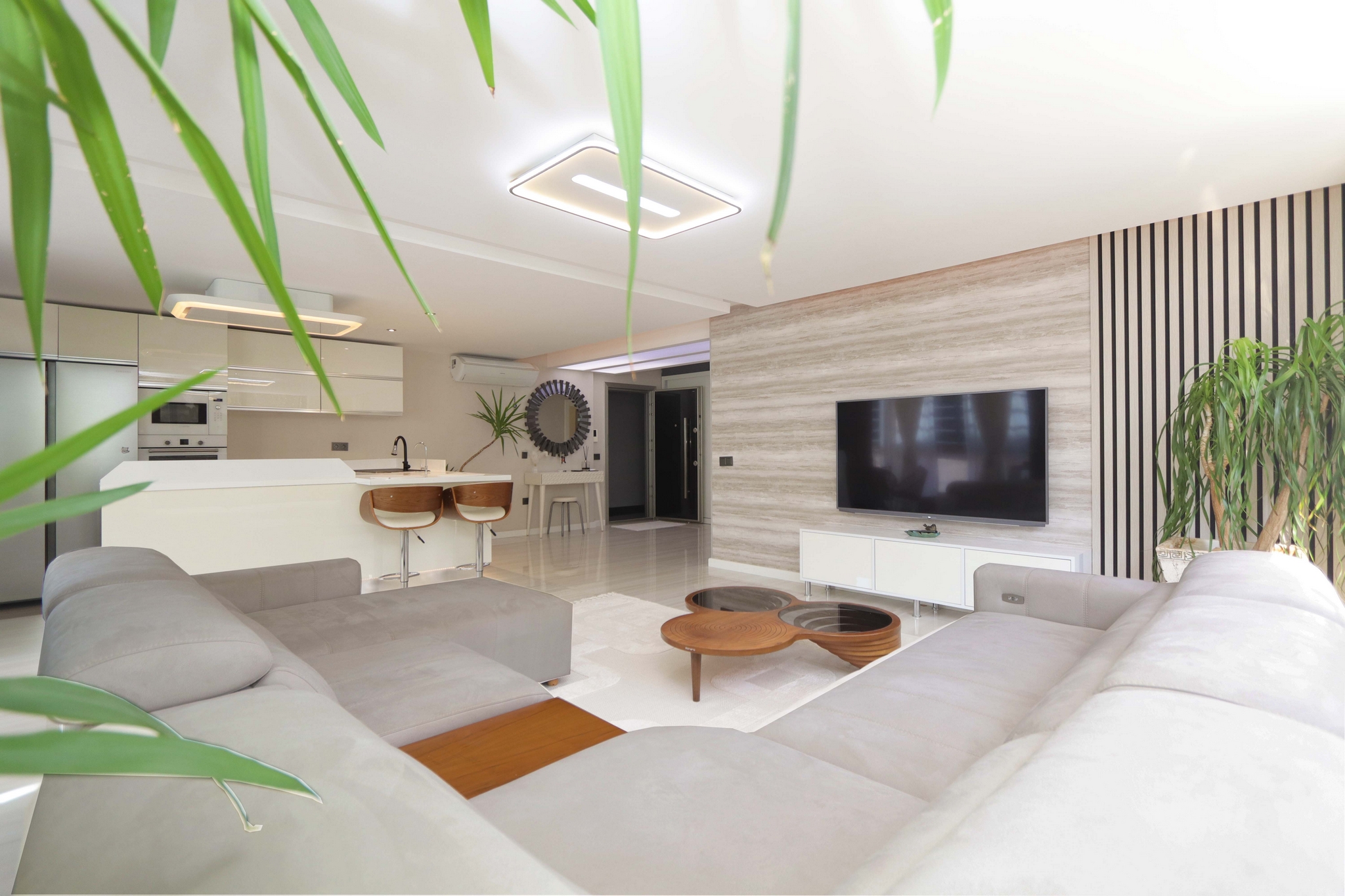 Kitchen-living room with an island, television and wood accent wall in a 2+1 residence for sale in Turkey