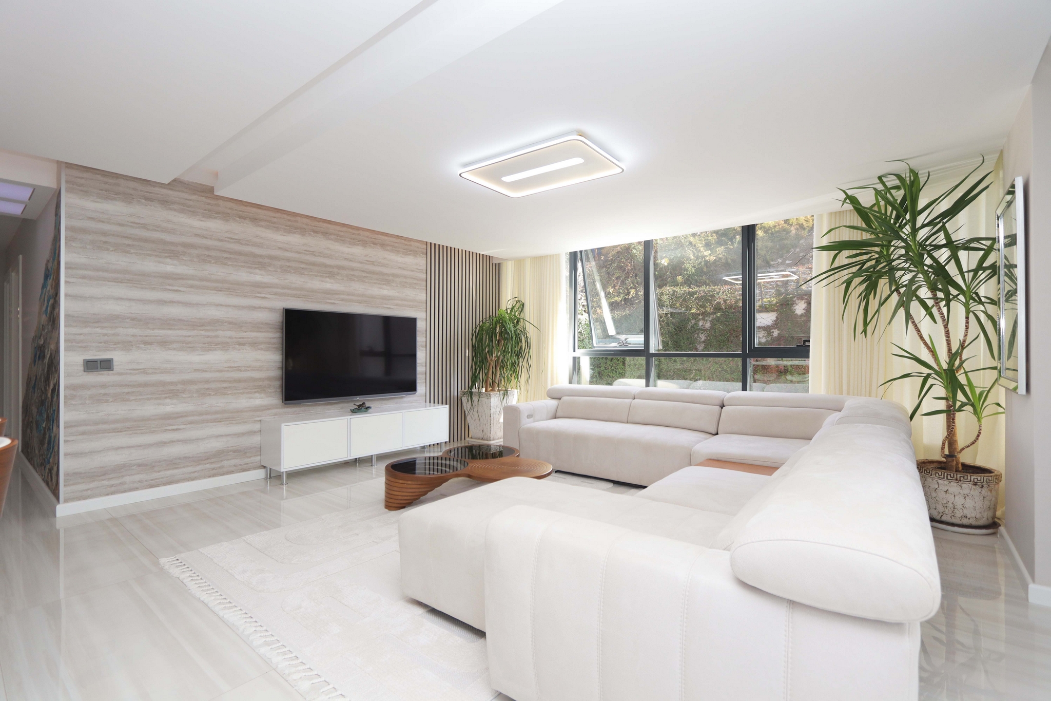 Living room with a corner sofa, television and panoramic windows in a flat in Kargicak