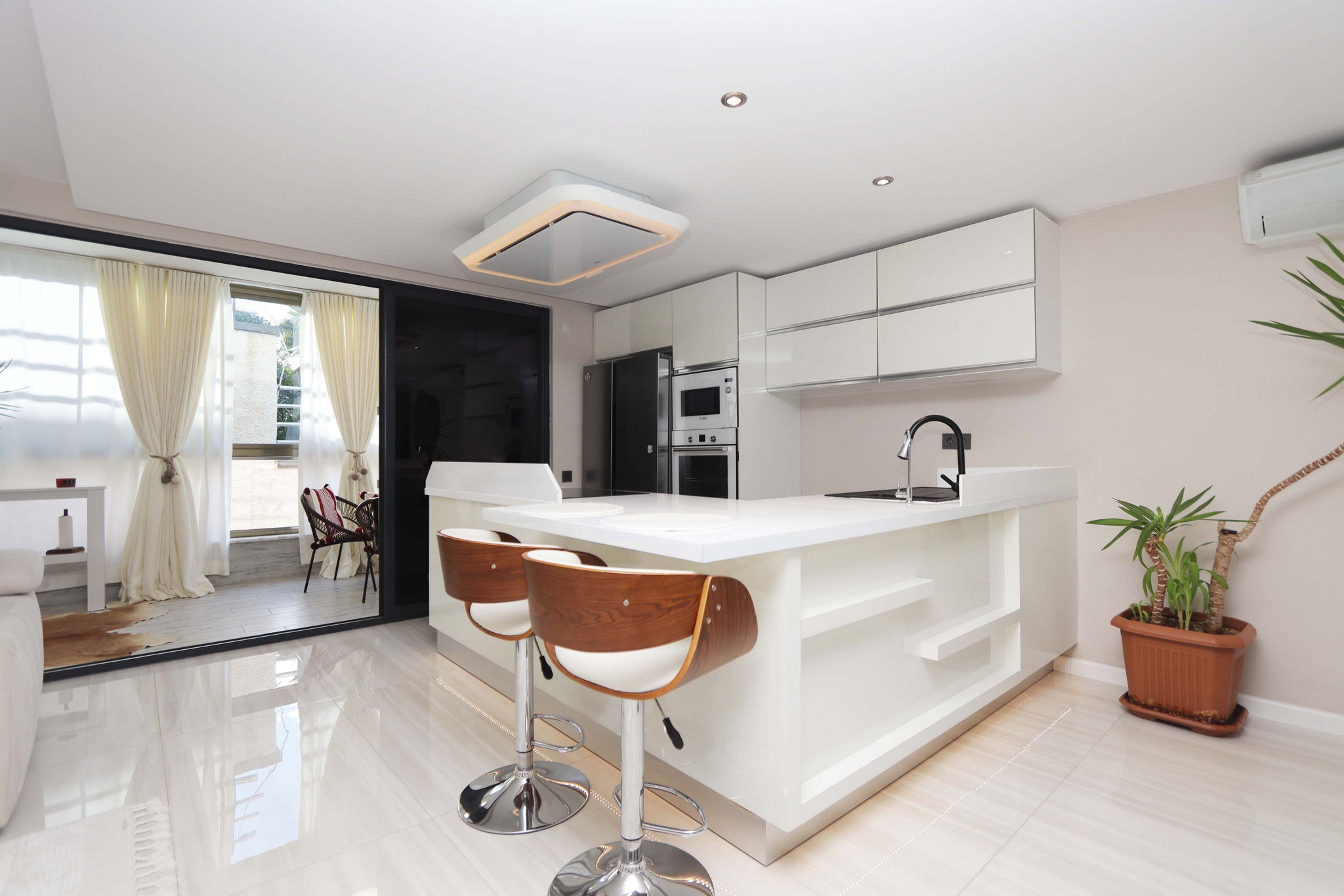Kitchen-living room with a white island, bar stools and built-in oven in a 2+1 apartment