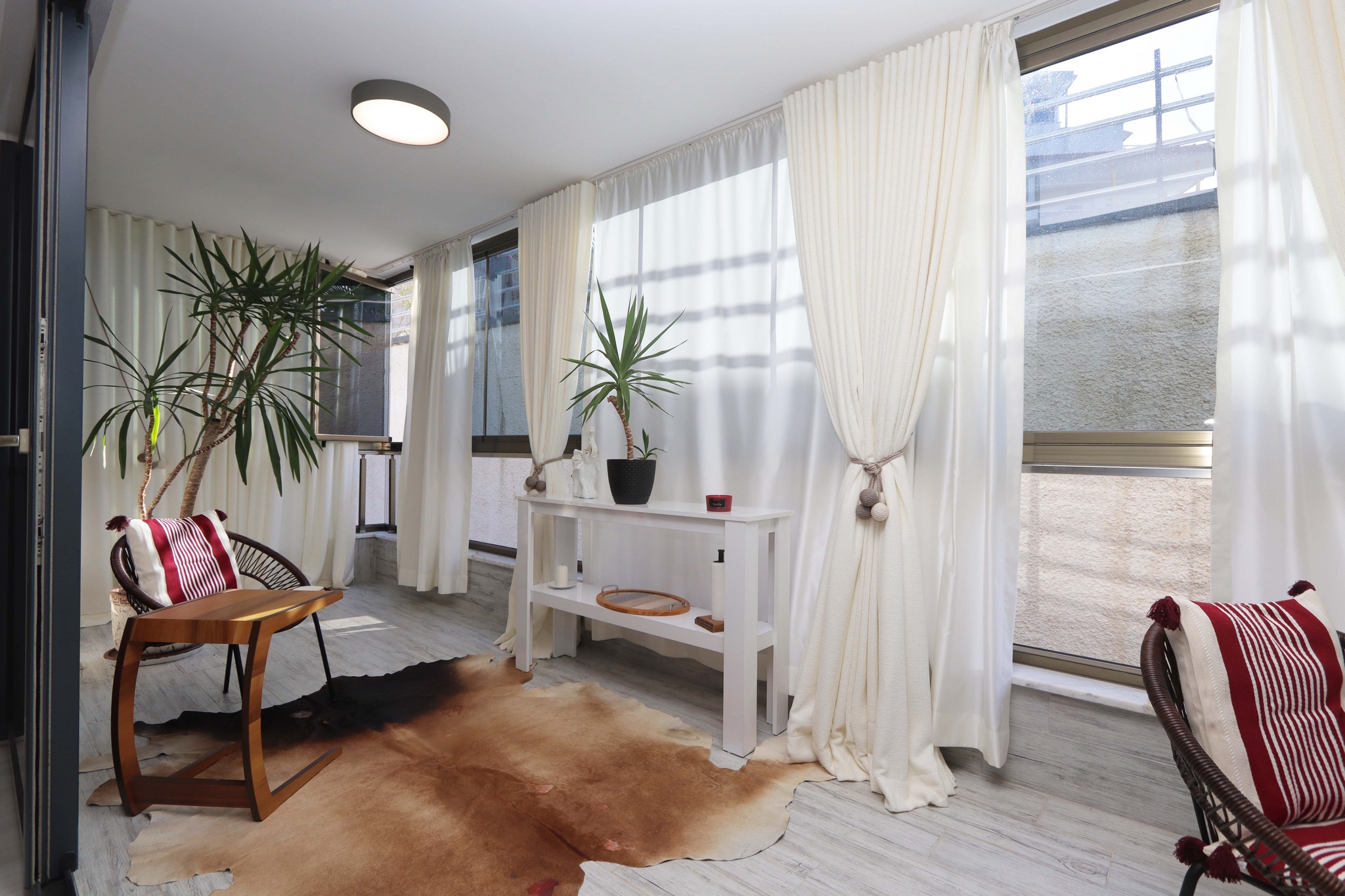 Glazed terrace with wicker chairs, small table and panoramic windows in a 2+1 apartment for sale
