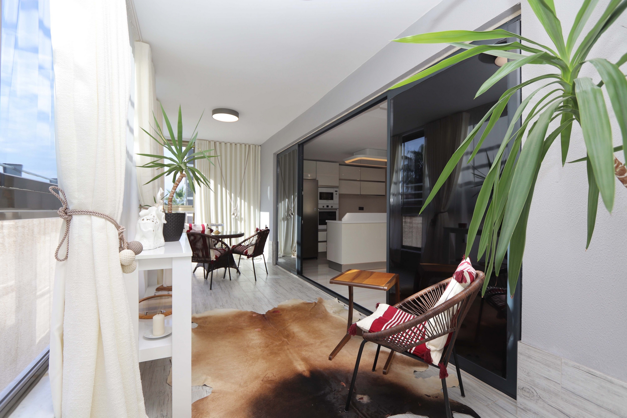 Long glazed terrace with wicker chair, small table and dining area in a 2+1 apartment