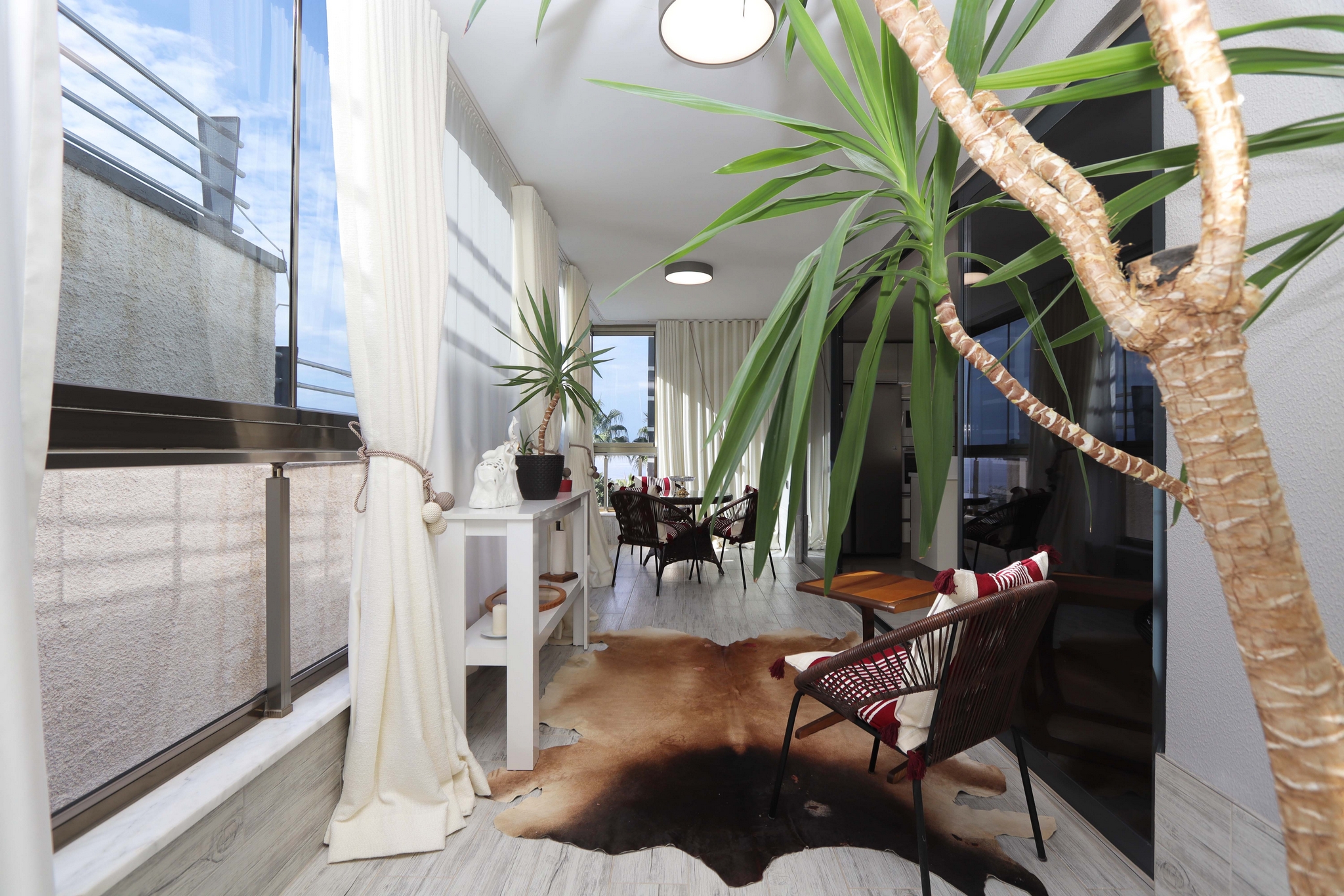 Glazed terrace with wicker chair, small table and dining area in a 2+1 flat in Kargicak, Turkey