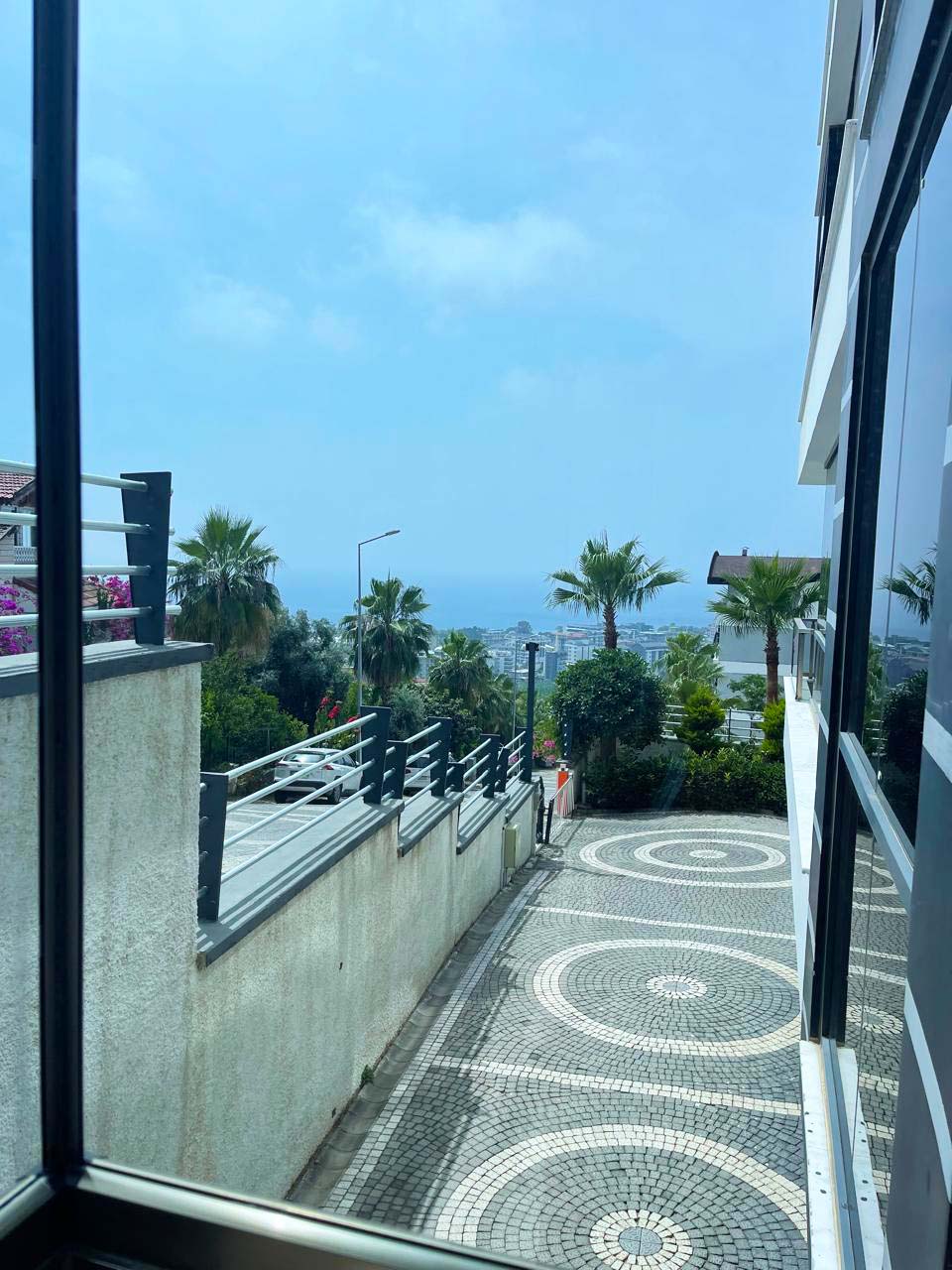 Palm-lined path with sea views and circular paving beside a building with flats for sale in Turkey