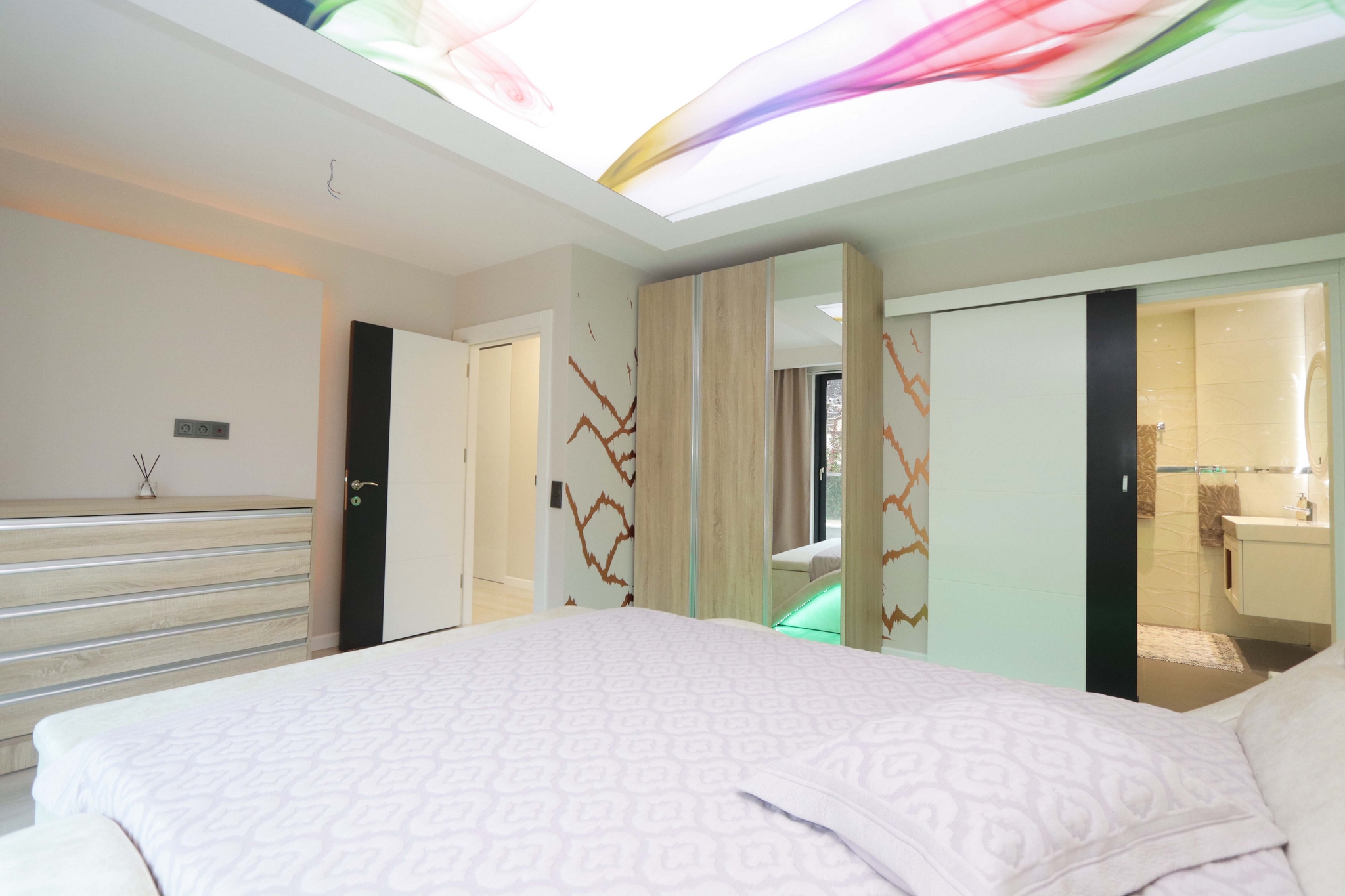 Bedroom with a textile bedspread, mirrored wardrobe and an open bathroom door