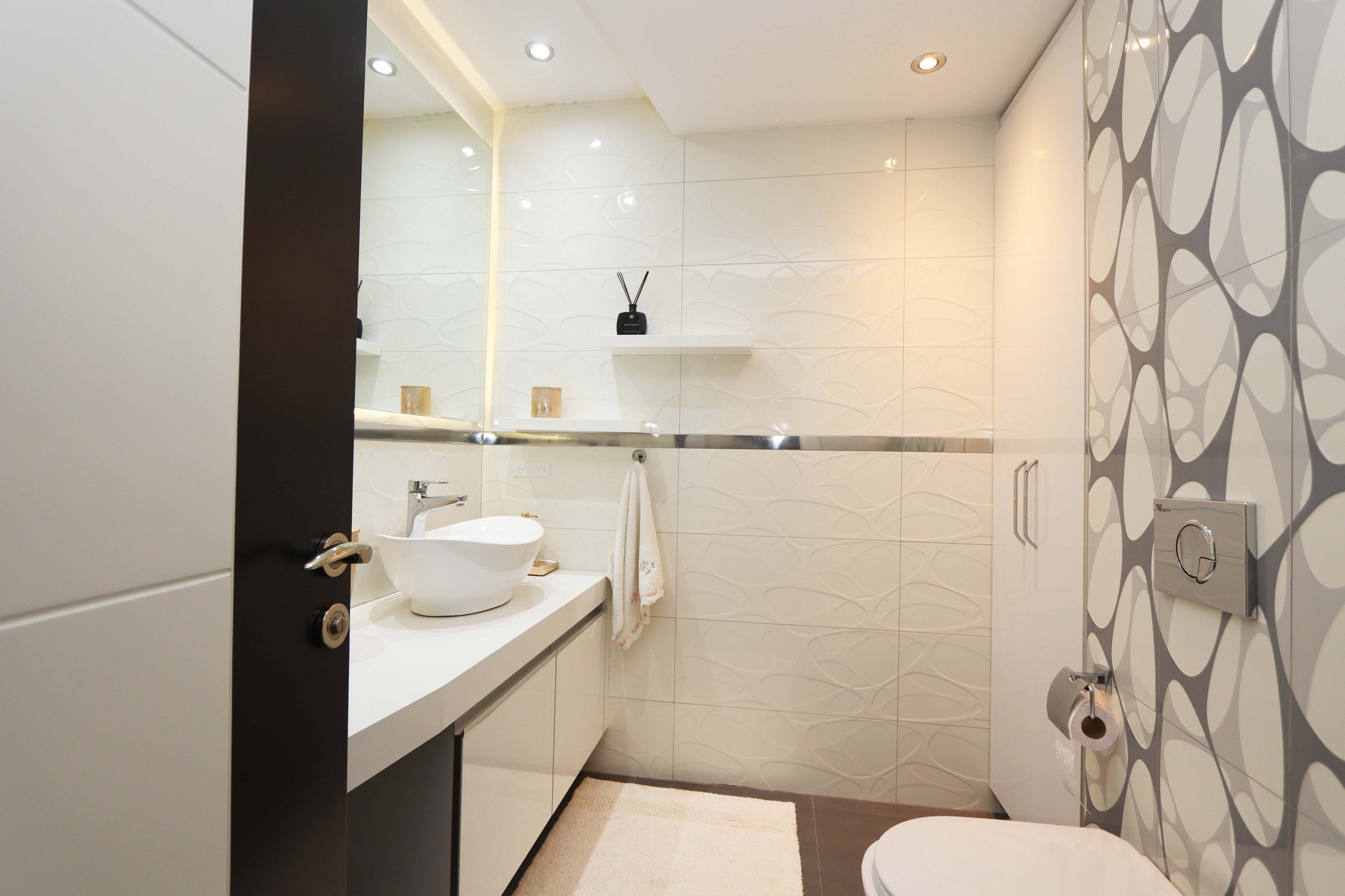 Bathroom with a white vessel sink, long vanity and geometric accent wall in a residence in Kargicak