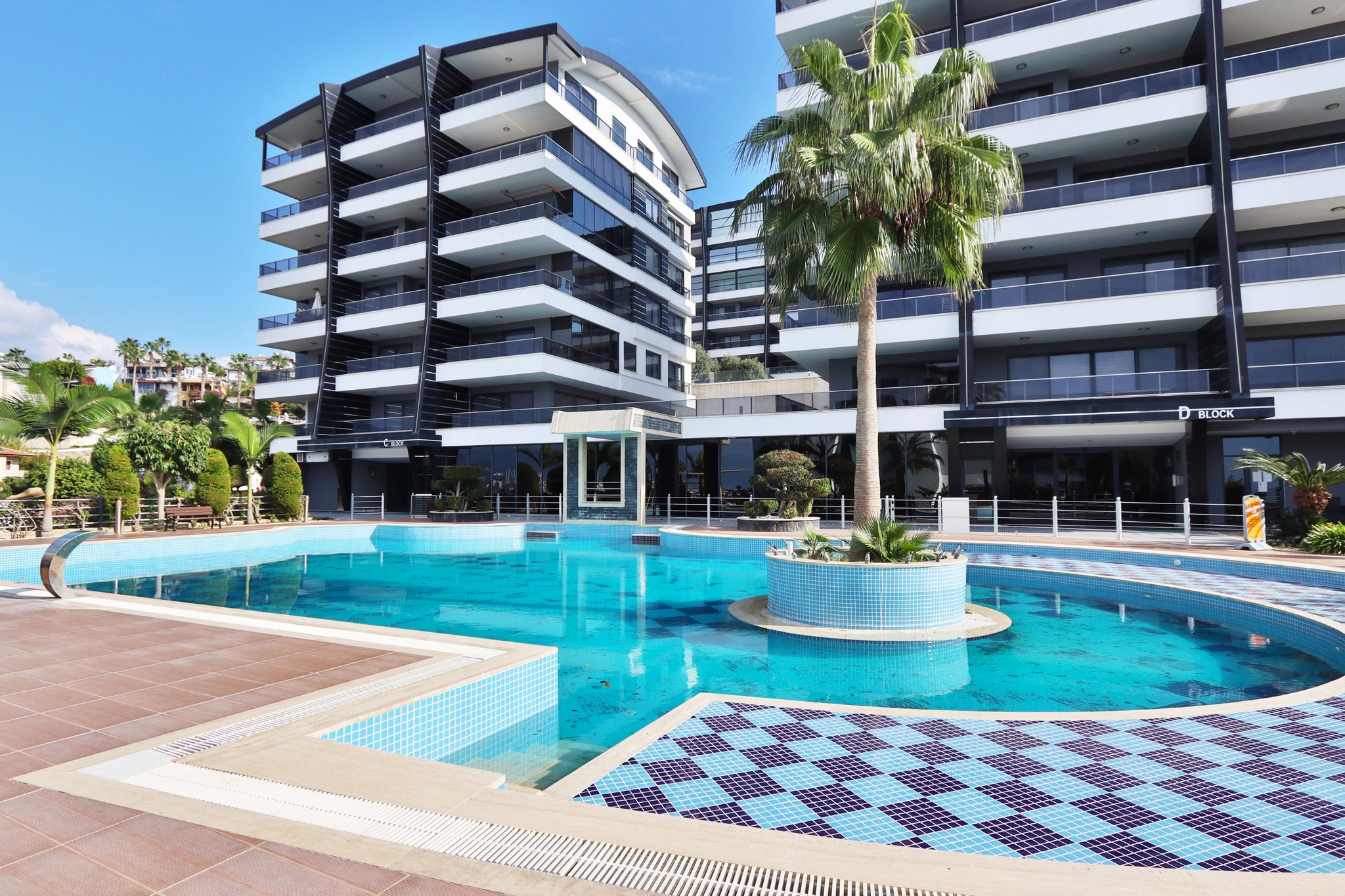 Curved outdoor pool with mosaic tiling and a palm island in Kargicak where residences are for sale