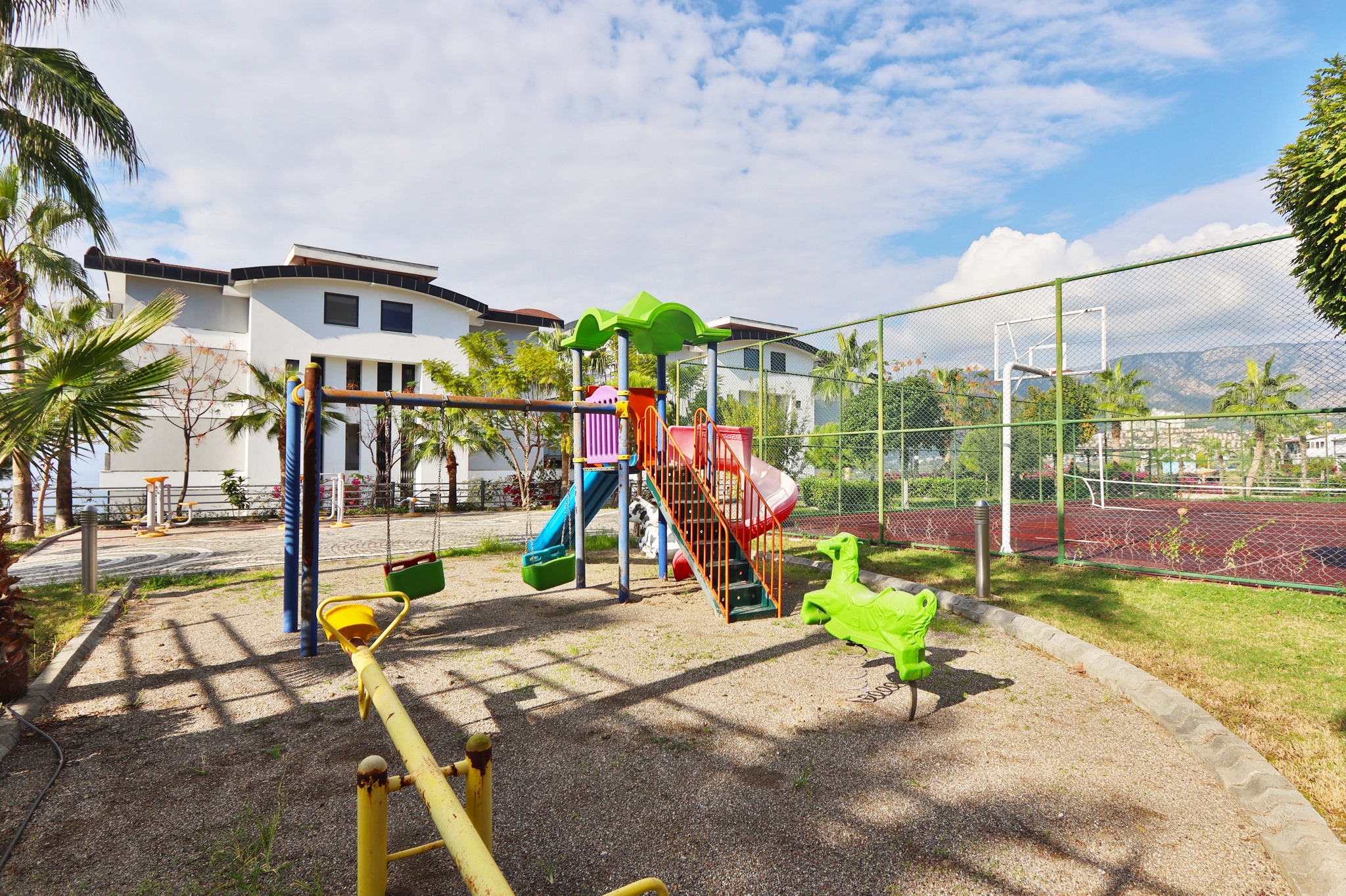 Children’s play area with a slide, swings and mountain views for residents of apartments in Kargicak