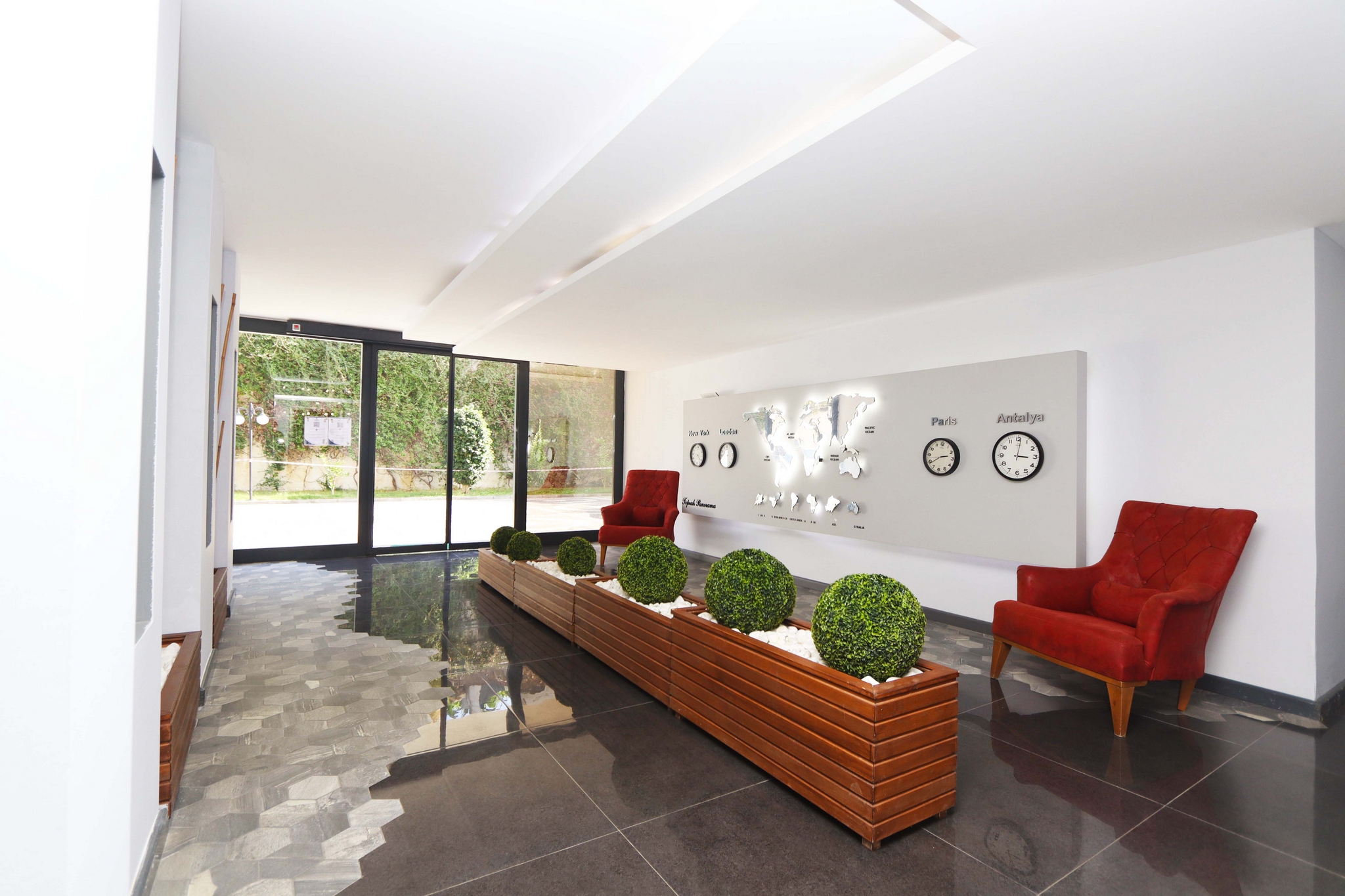 Lobby with red armchairs, a world map and glass entrance doors showing flats for sale in Turkey
