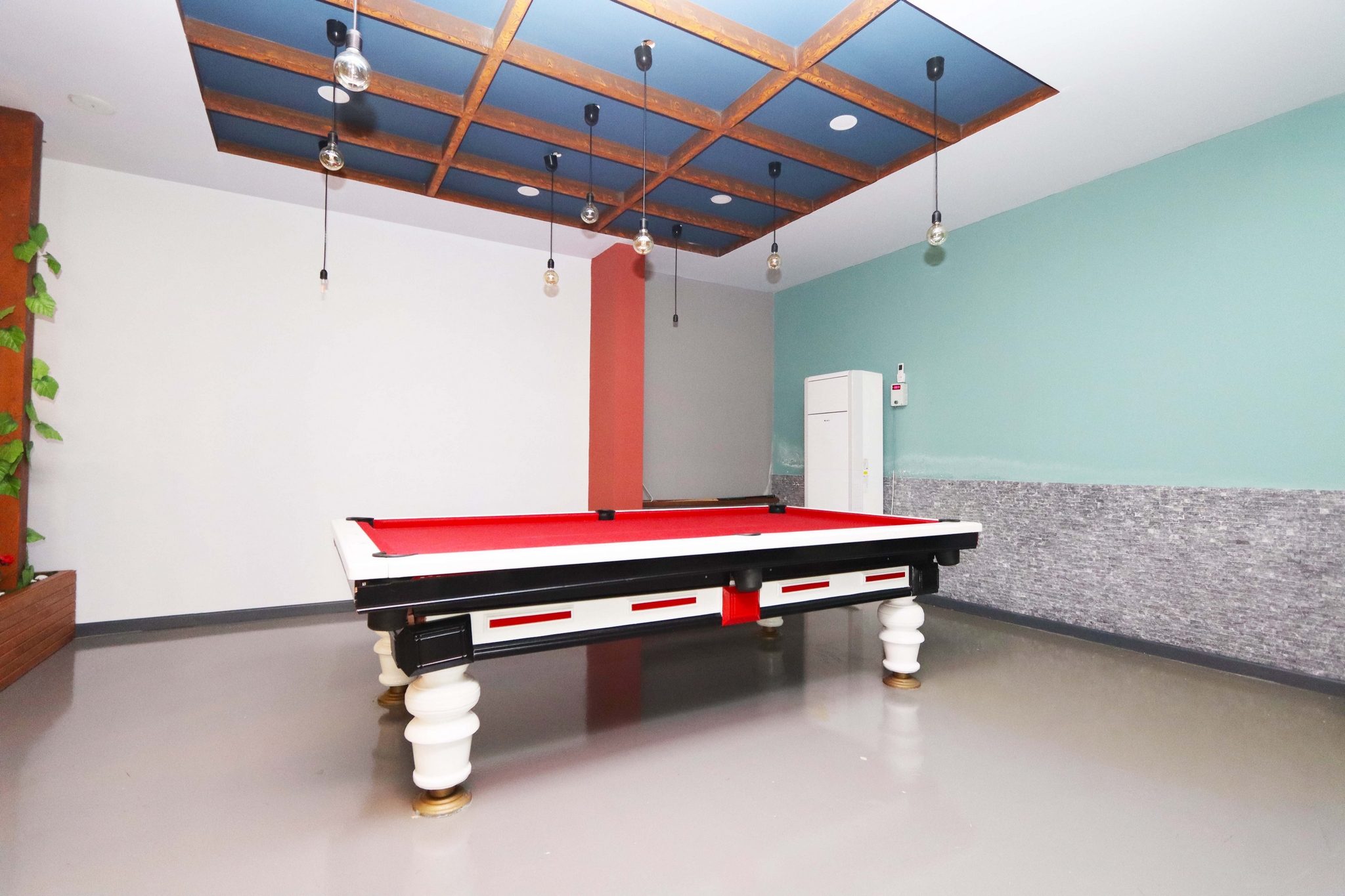 Billiard room with a pool table, pendant lights and mosaic wall finish in a complex with apartments