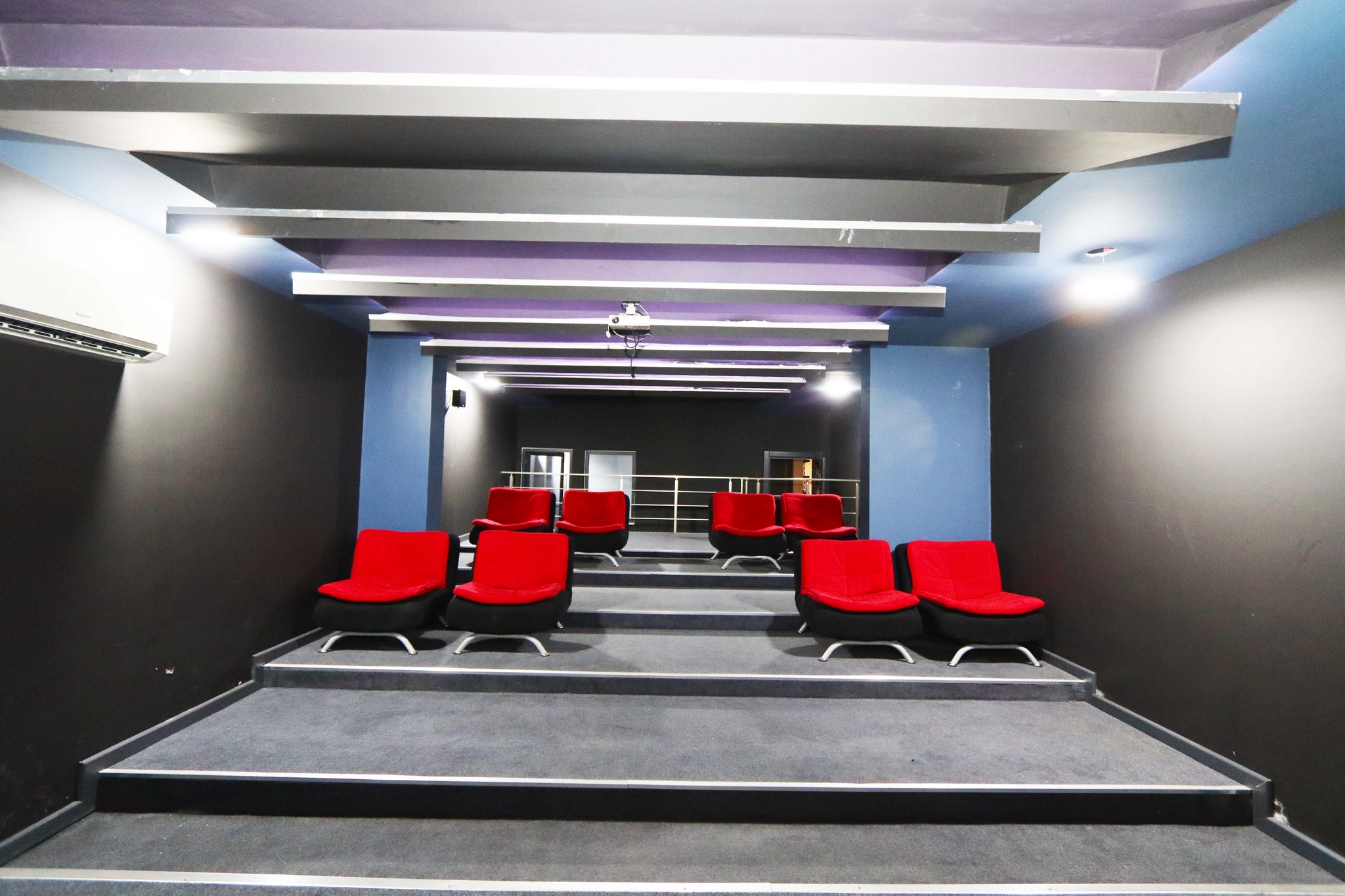 Cinema room with red seats, stepped rows and a ceiling projector in Kargicak