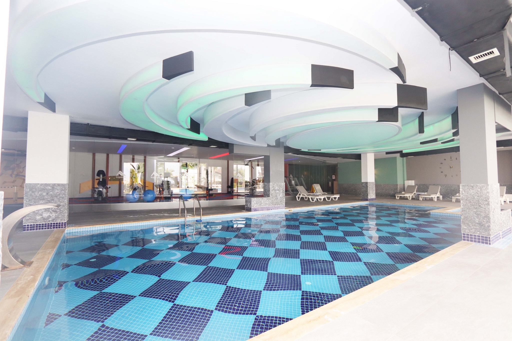 Indoor pool with columns, loungers and panoramic windows showing apartments for sale in Turkey