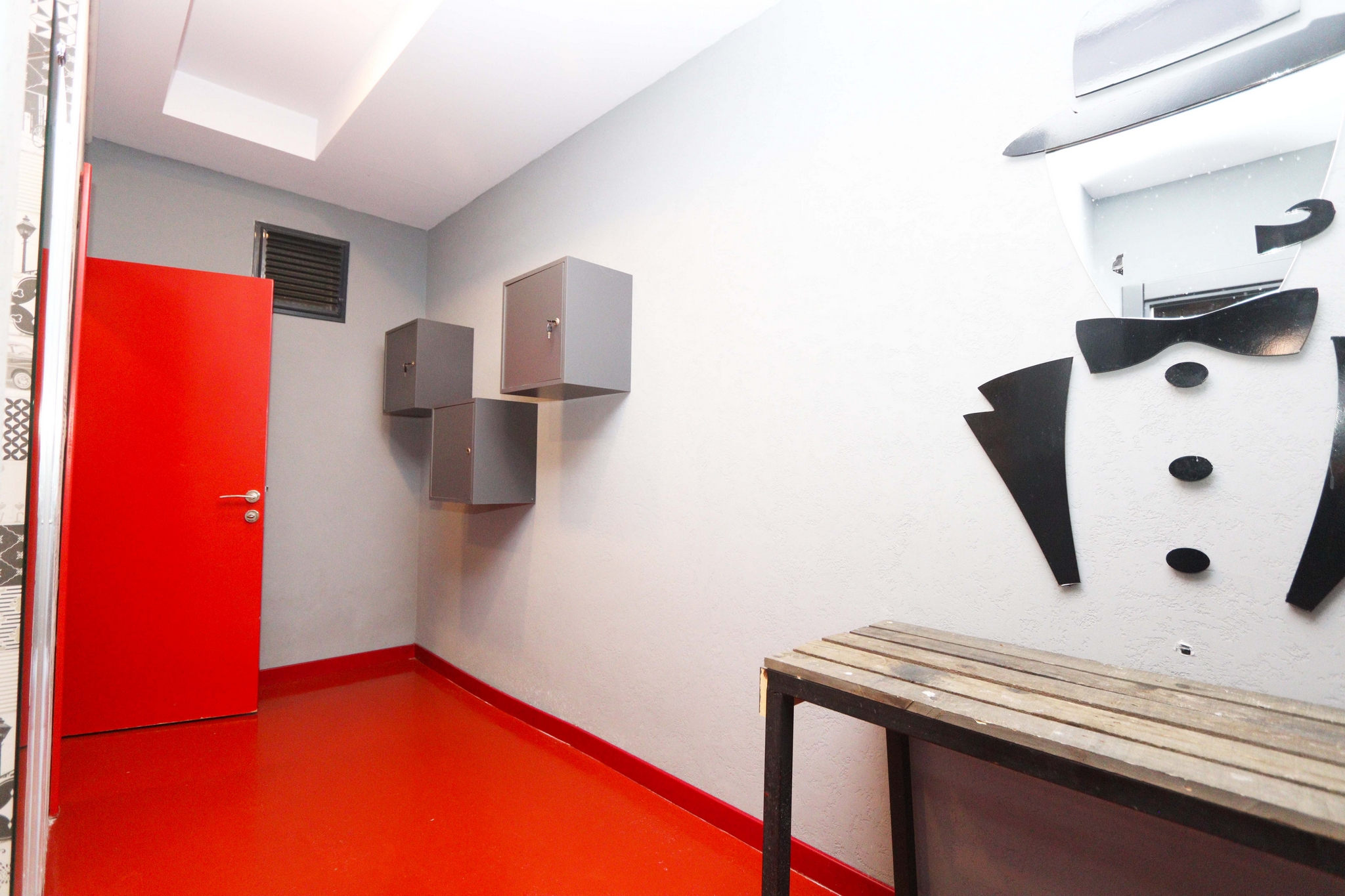 Changing room with a wooden bench, lockers and red door in a complex with apartments in Kargicak