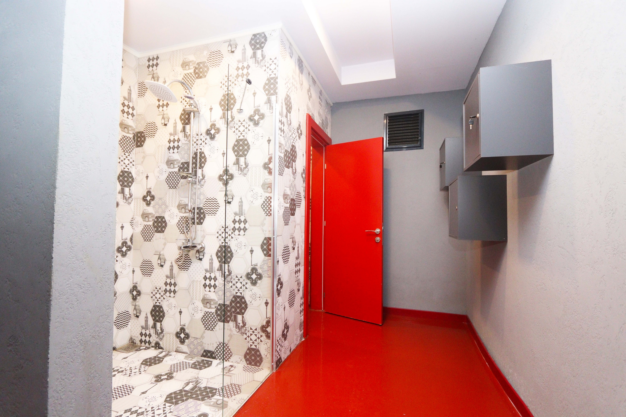 Bathroom with a red door, glass shower partition and wall cabinets for residents of flats