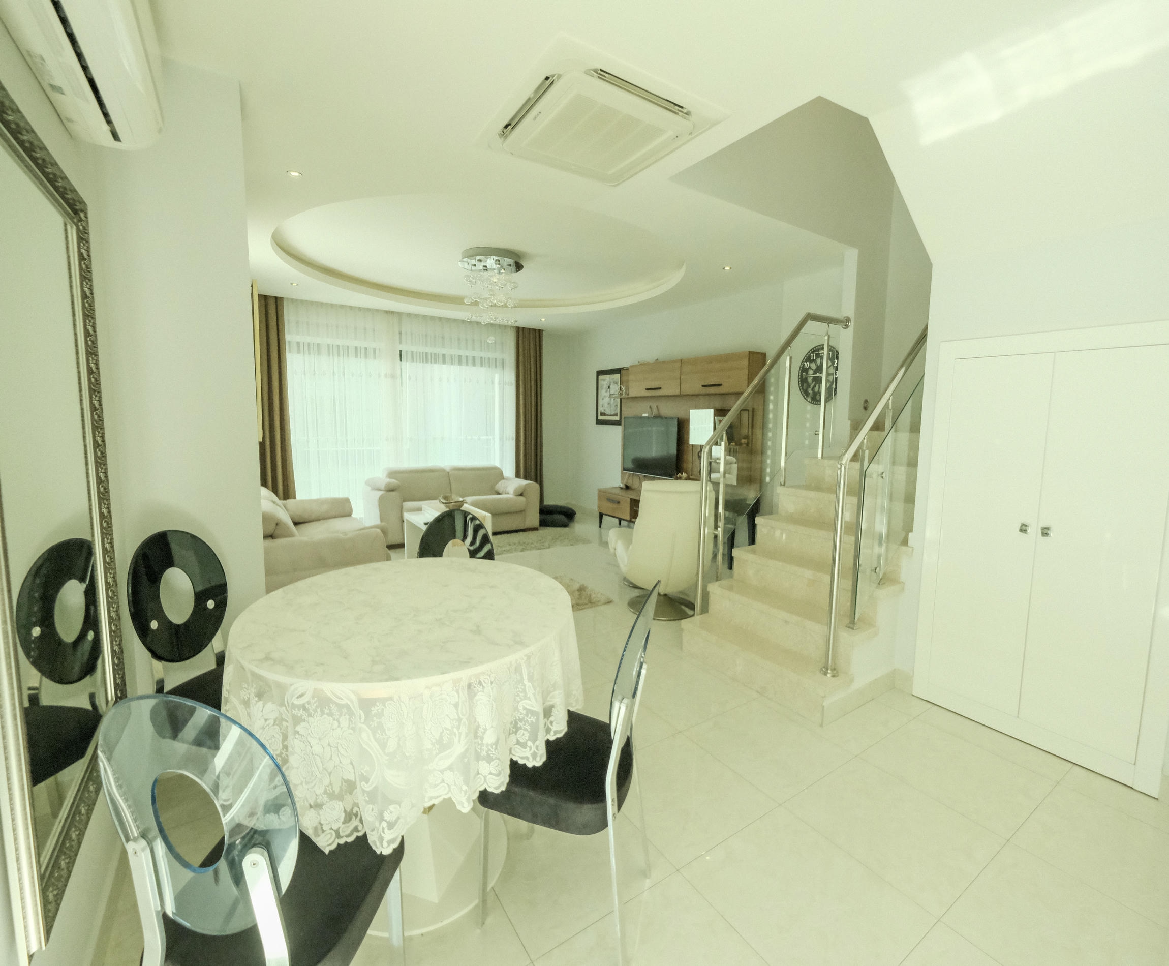 Dining room with a round table and glass-railed stairs in an apartment