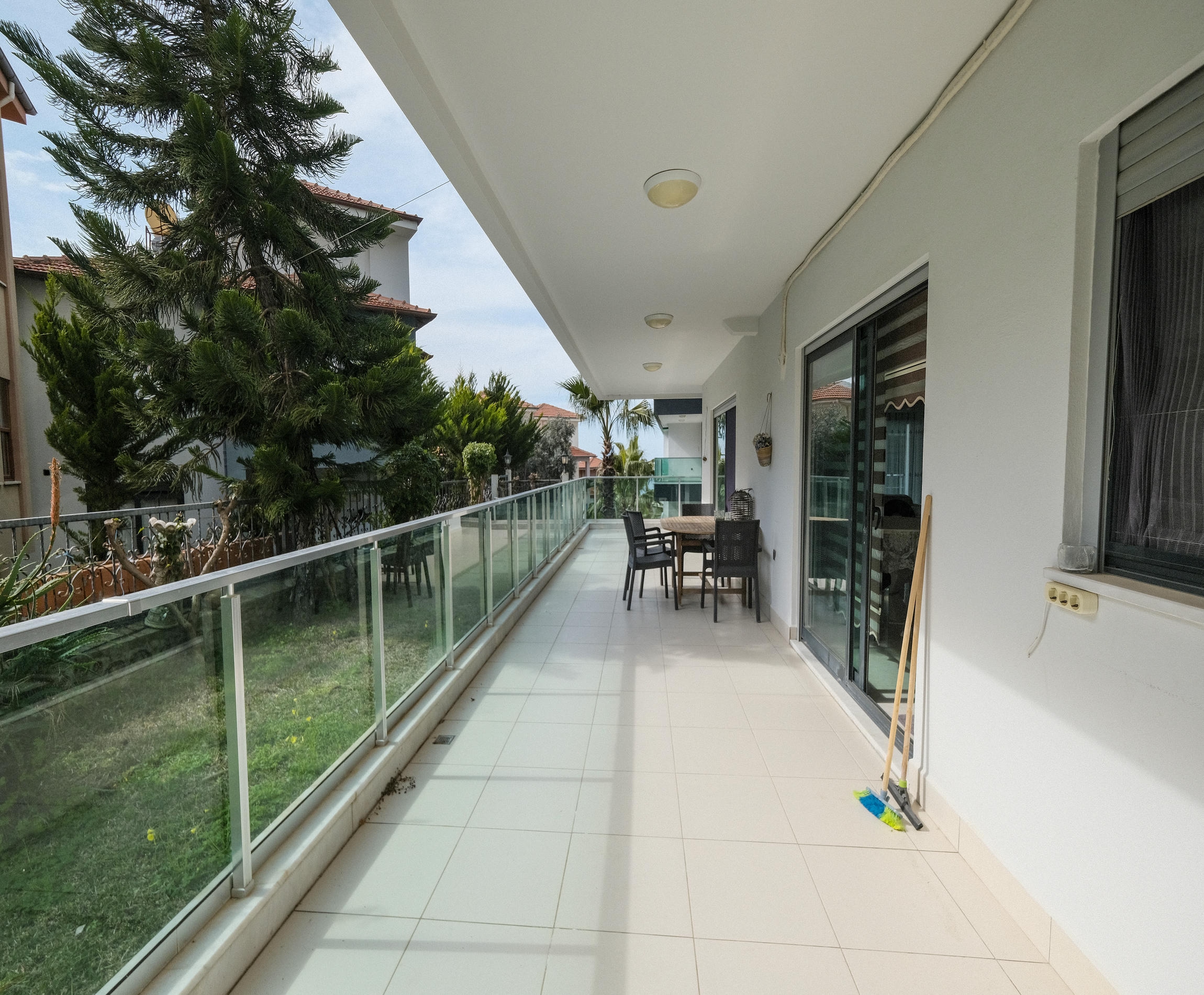 Terrace with a glass railing and outdoor table overlooking a green courtyard in Kargicak