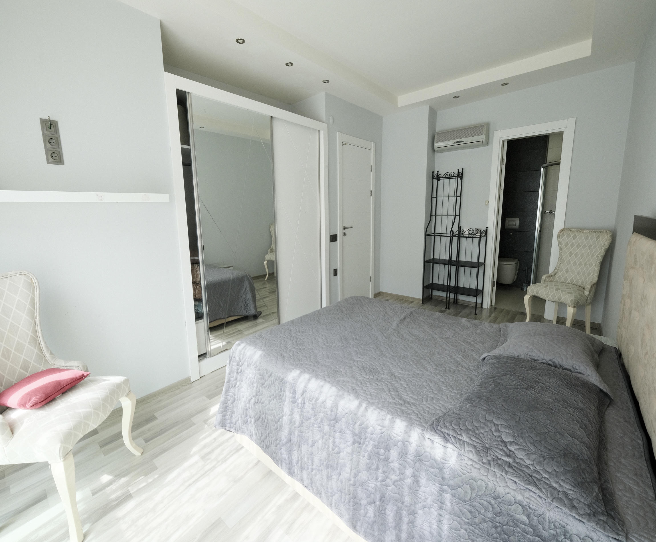 Bedroom with a double bed, mirrored wardrobe and door to the bathroom in an apartment