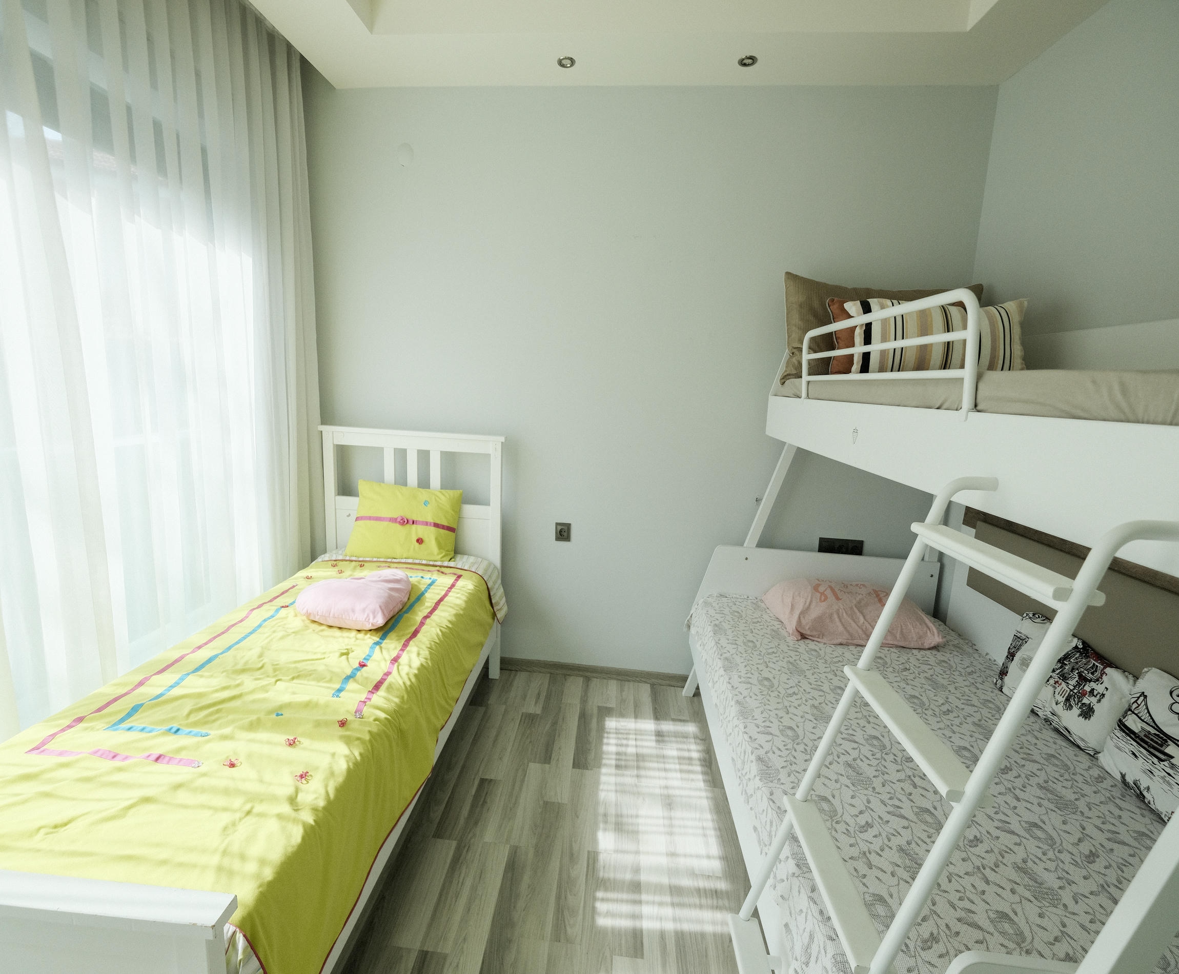 Children's bedroom with bunk and single beds beside a panoramic window in an apartment in Kargicak