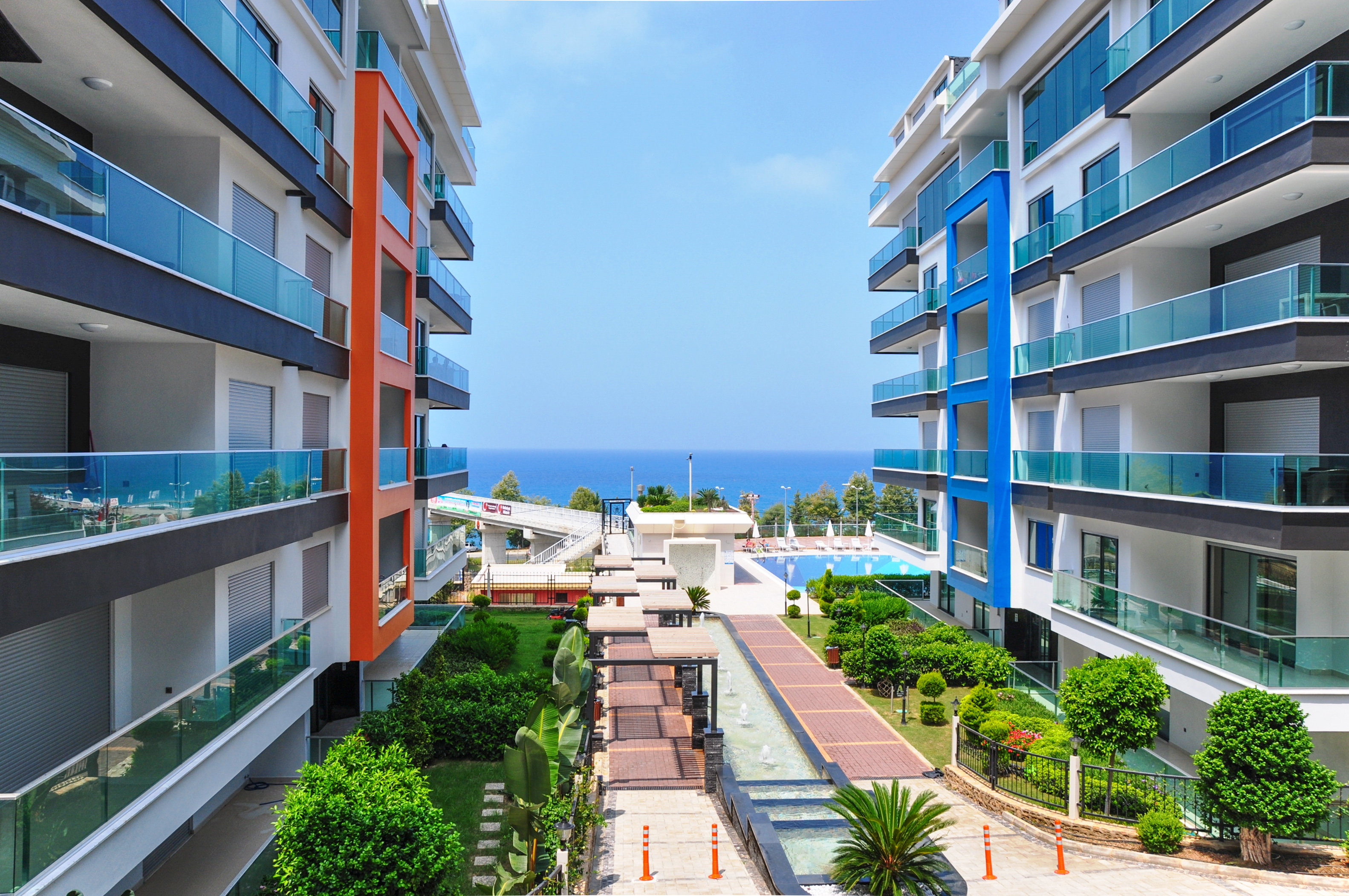 Paved walkway with planted beds and a central pool on a residence grounds in Kargicak where apartments are for sale