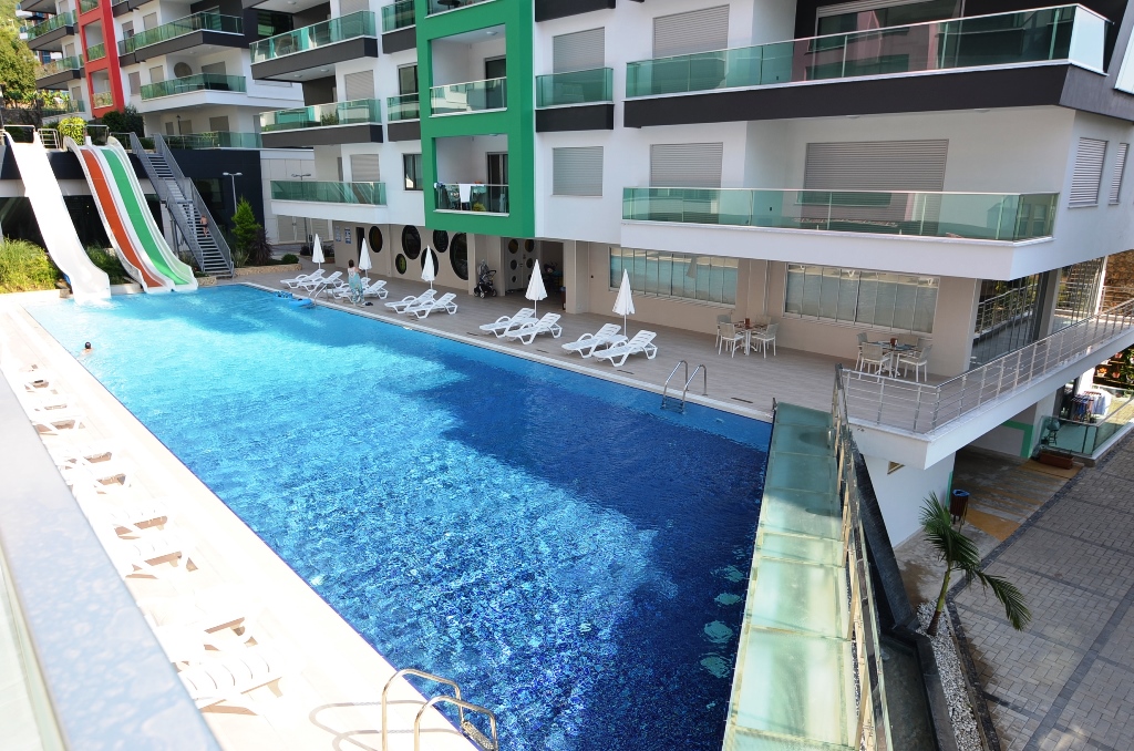 Outdoor pool with slides and white loungers for residents of apartments in a complex in Turkey