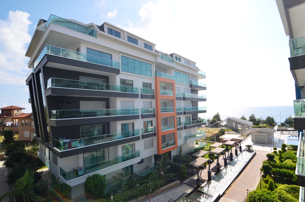 Residential building with panoramic windows above a pool in Kargicak where apartments are for sale